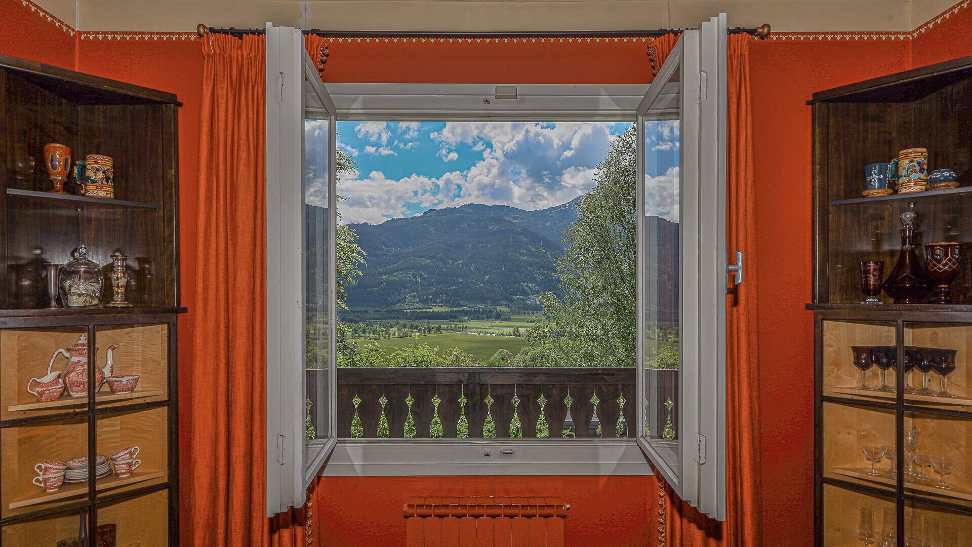 Fensterblick aus dem Esszimmer auf die weite Berglandschaft und grüne Täler.