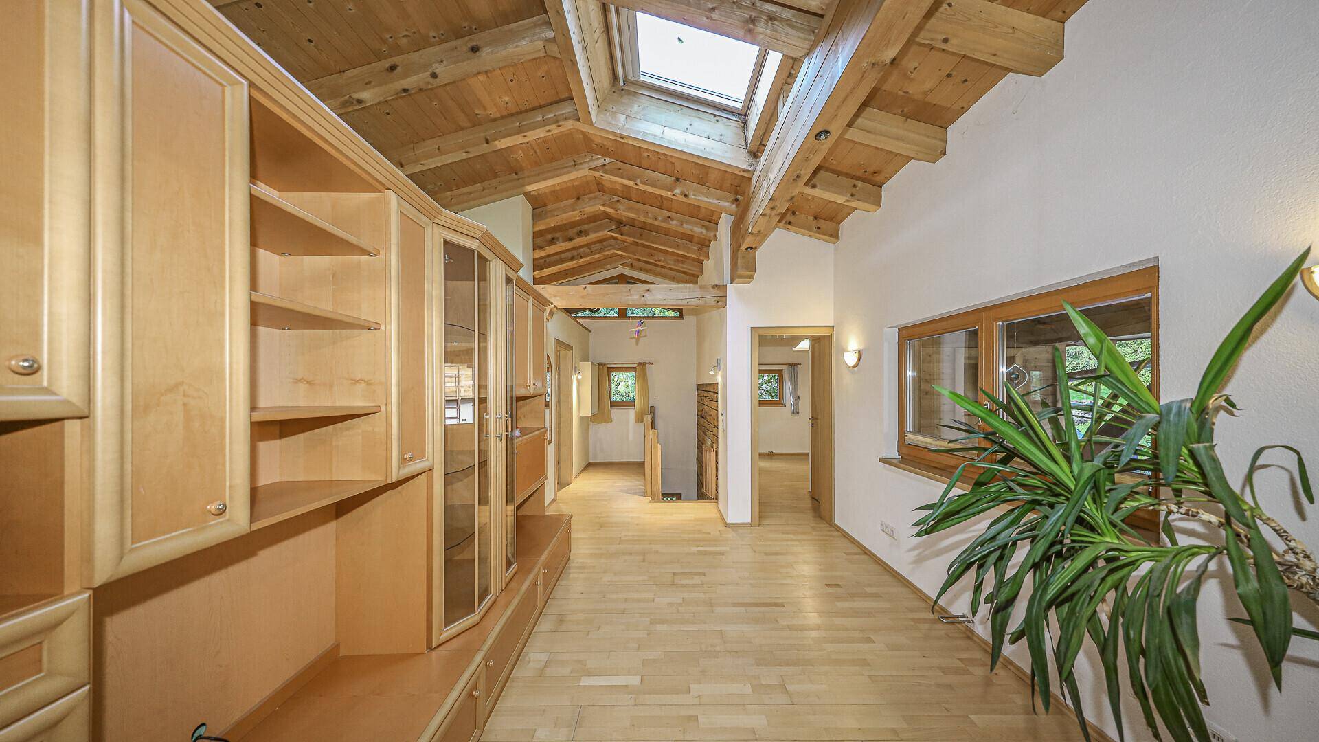 Geräumiger Wohnbereich mit Holzbalkendecke, Dachfenstern und langen Einbauschränken.