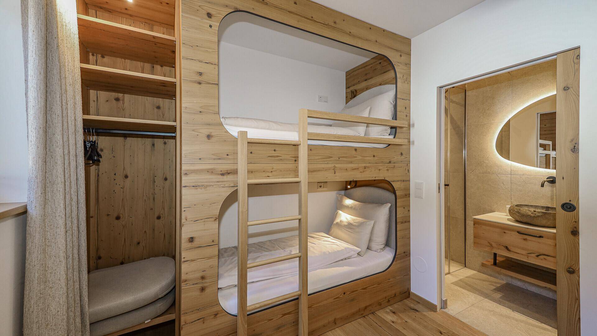 Kinderzimmer mit eingebauten Etagenbetten aus Holz und angrenzendem modernem Badezimmer.