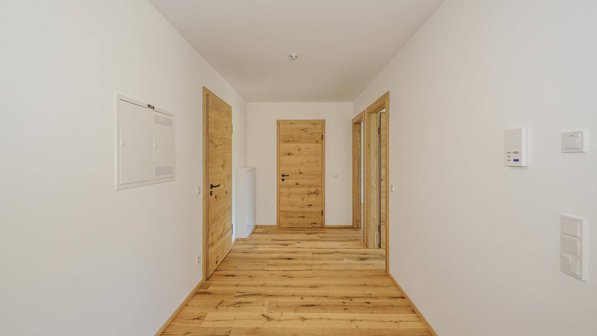Heller Flur mit Holzboden und mehreren Holztüren, der zu den verschiedenen Räumen führt.