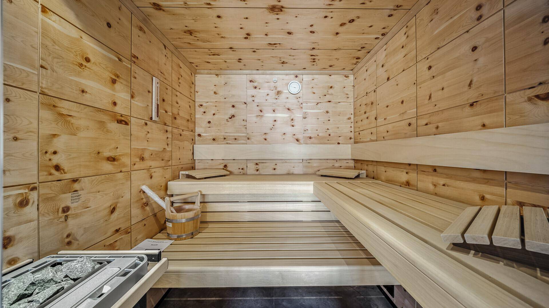 Traditionelle Holzsauna mit Bänken und Saunaofen für entspannende Momente.