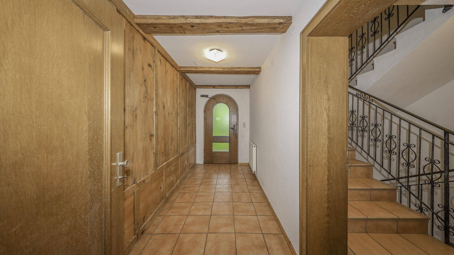 Geräumiger Flur mit Fliesenboden, Holzvertäfelung und Treppenaufgang.