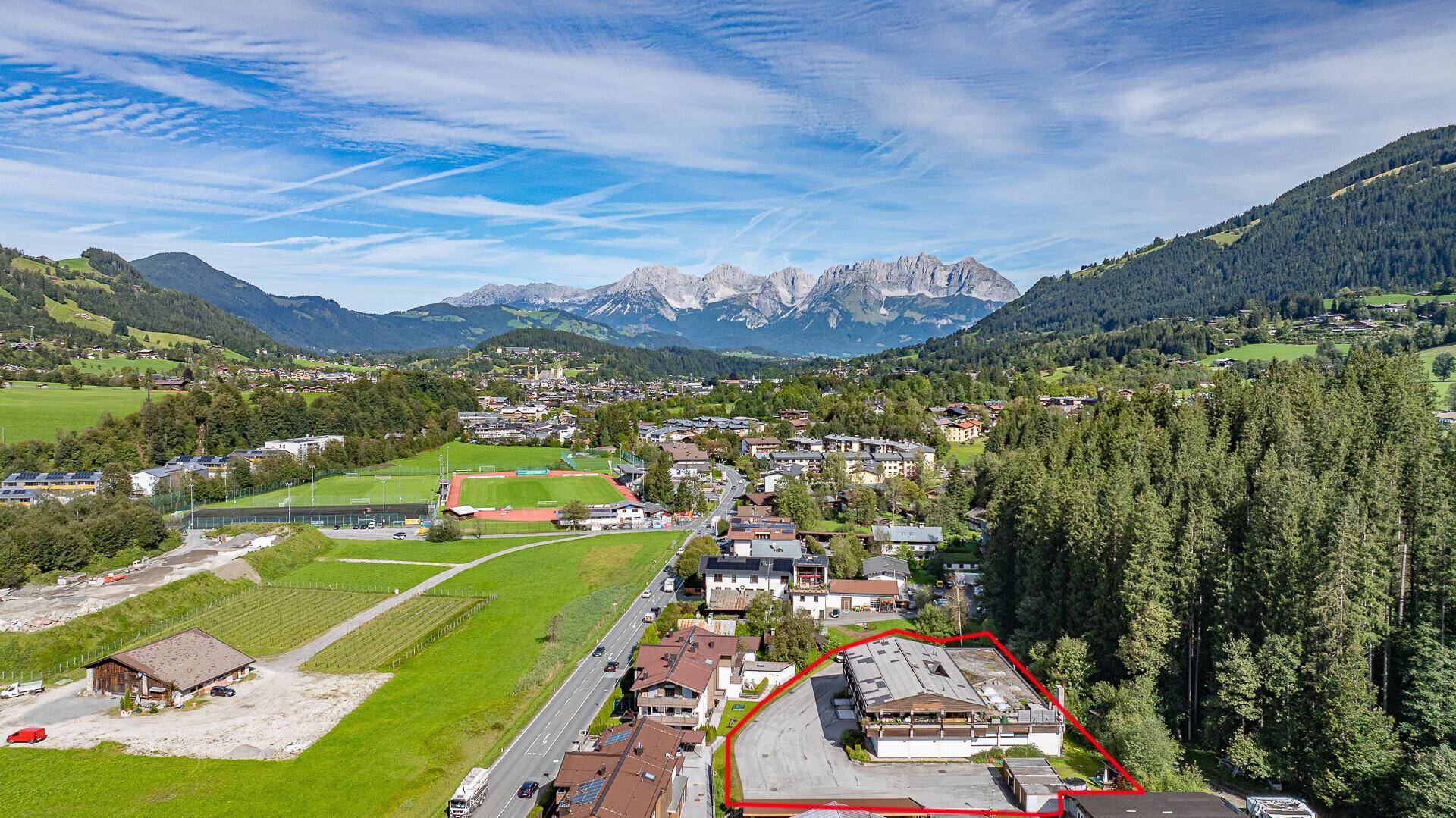 Weitläufige Luftaufnahme des Grundstücks mit roter Umrandung, umgeben von Natur und alpiner Landschaft.