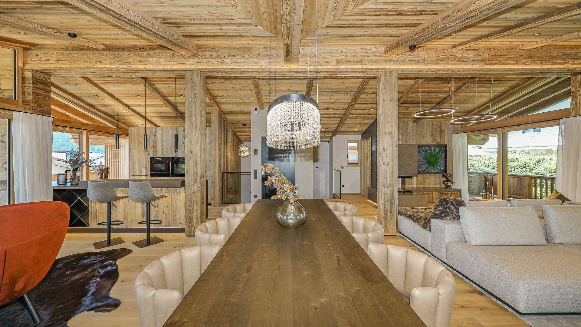 Offener Wohnbereich mit Esszimmer und Blick auf die moderne Küche im alpinen Design.