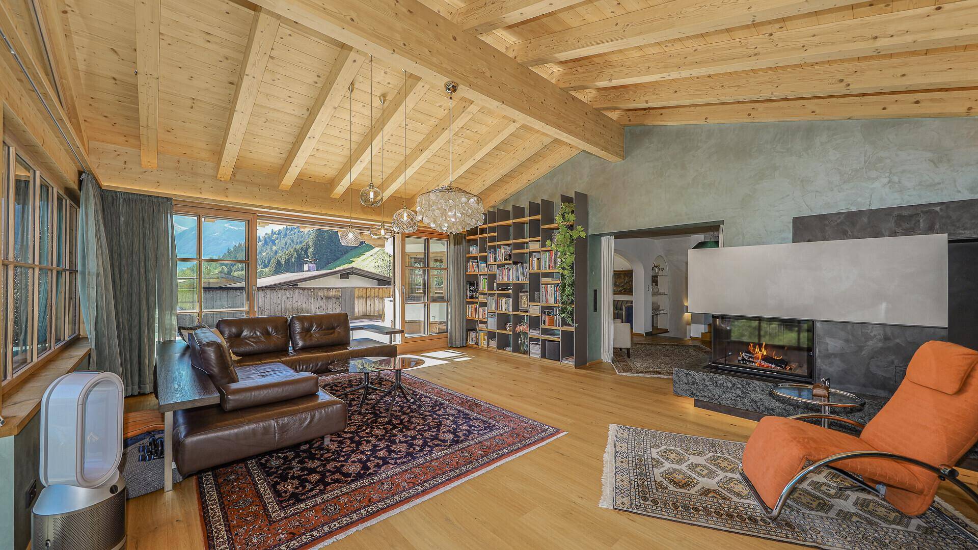 Großzügiges Wohnzimmer mit Kamin, Ledersofa und Zugang zu einem sonnigen Außenbereich.