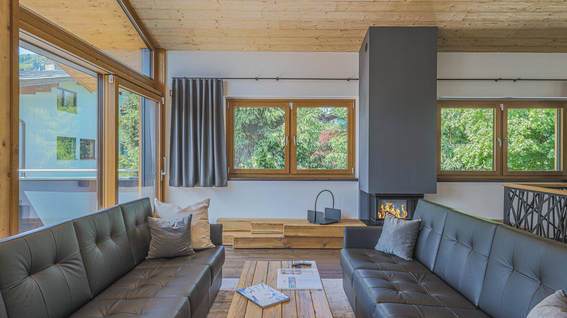 Heller Wohnbereich mit Kamin, großen Fenstern und Blick ins Grüne, ideal zum Entspannen.