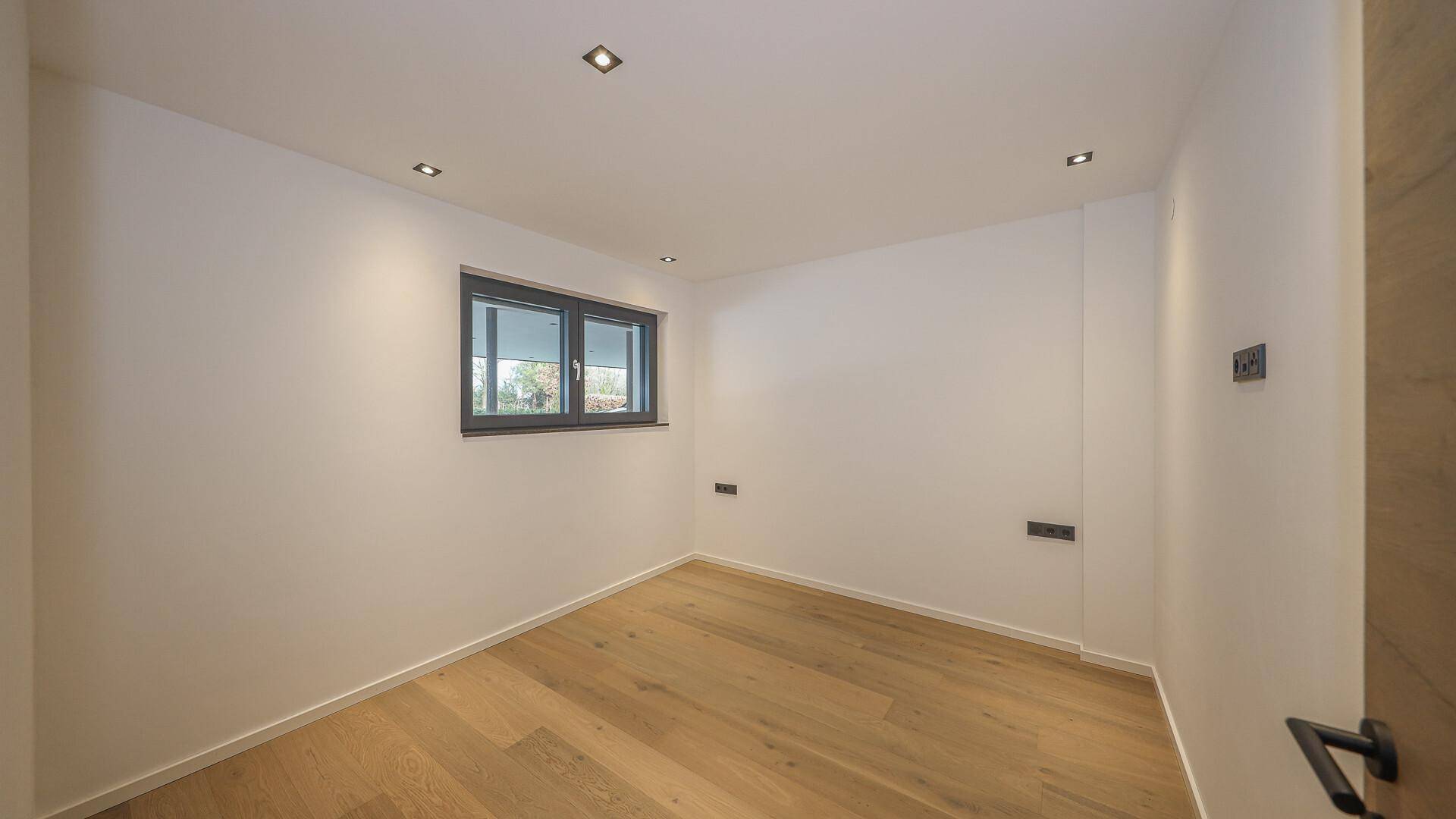 Kleines Zimmer mit Holzboden und Fenster, ideal als Gästezimmer oder Büro.