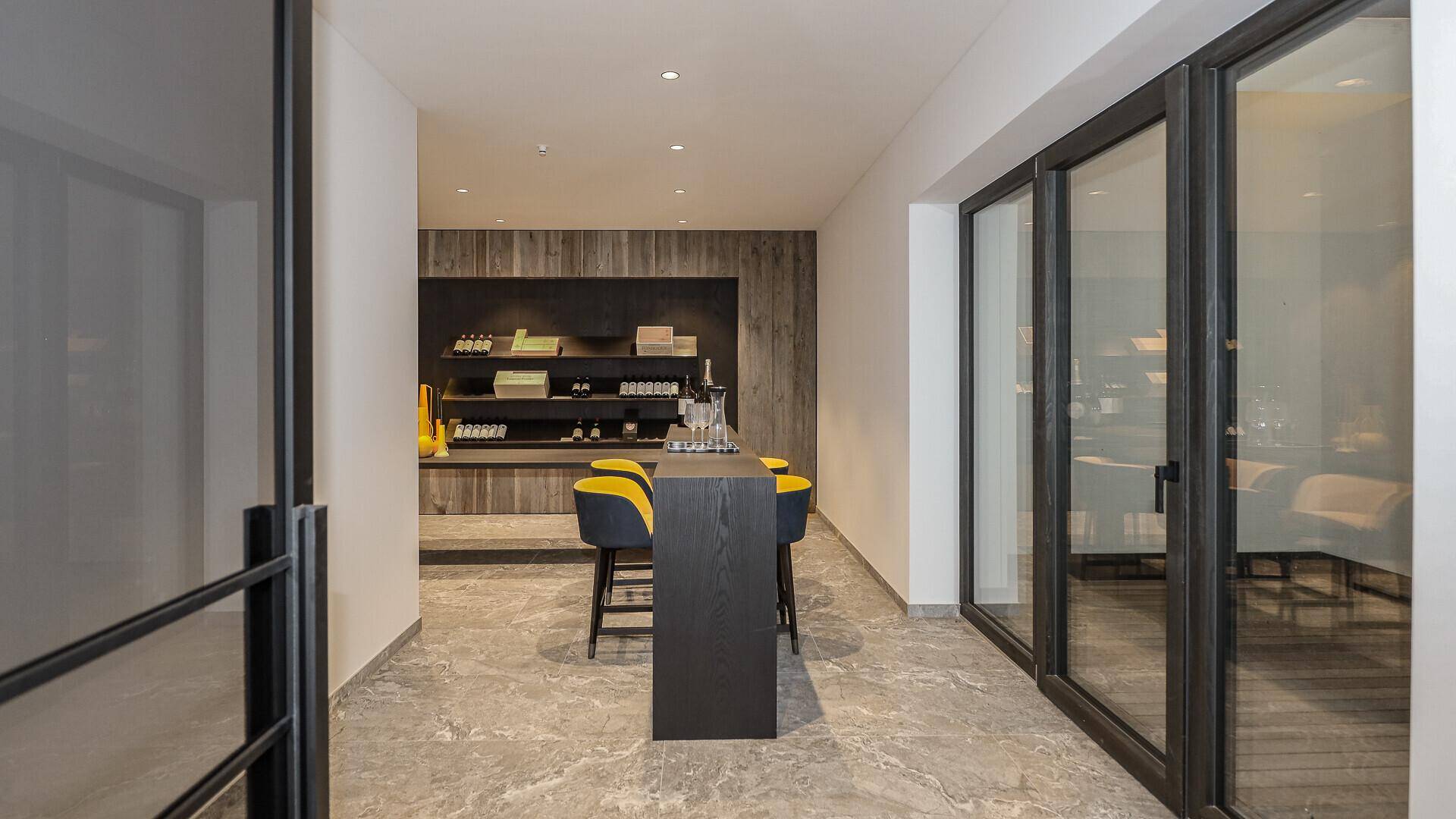 Stilvolle Bar mit Hockern und Regalen, ideal für gesellige Abende in modernem Ambiente.