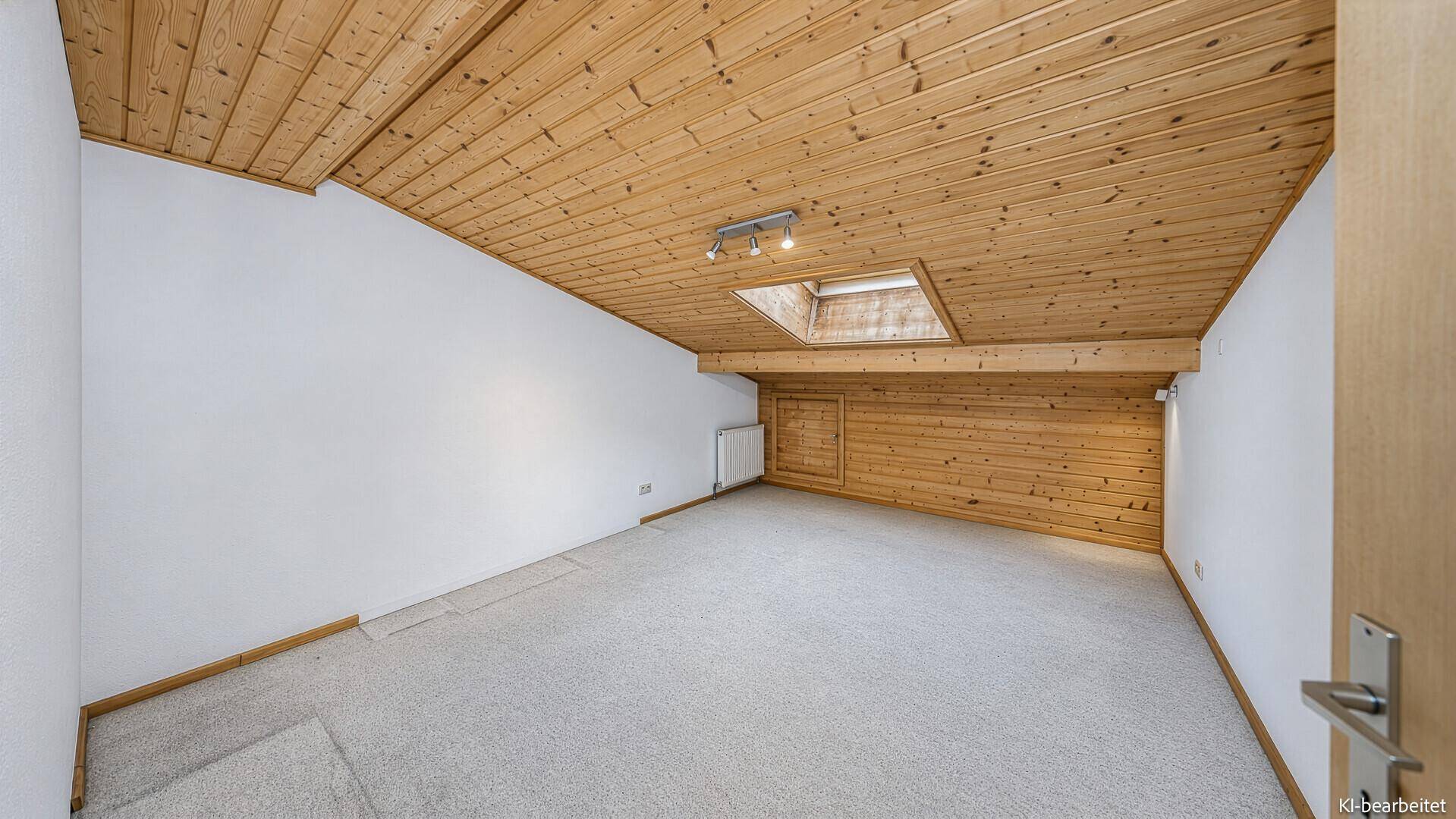 Geräumiges Schlafzimmer im Dachgeschoss mit Teppichboden, Holzbalkendecke und Dachfenster.