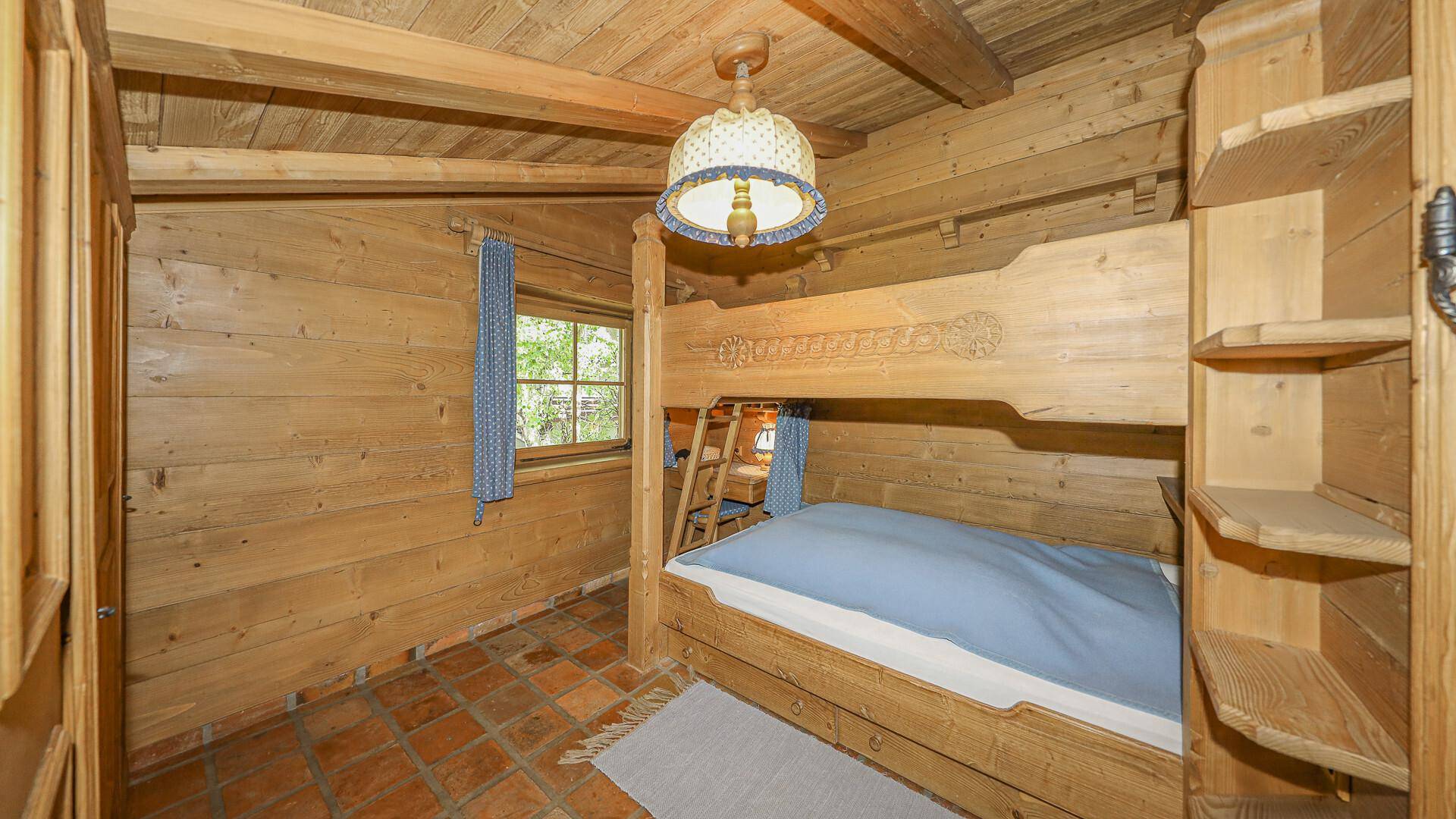 Kinderzimmer mit Etagenbett, Holzvertäfelung und Fenster mit Blick ins Grüne.