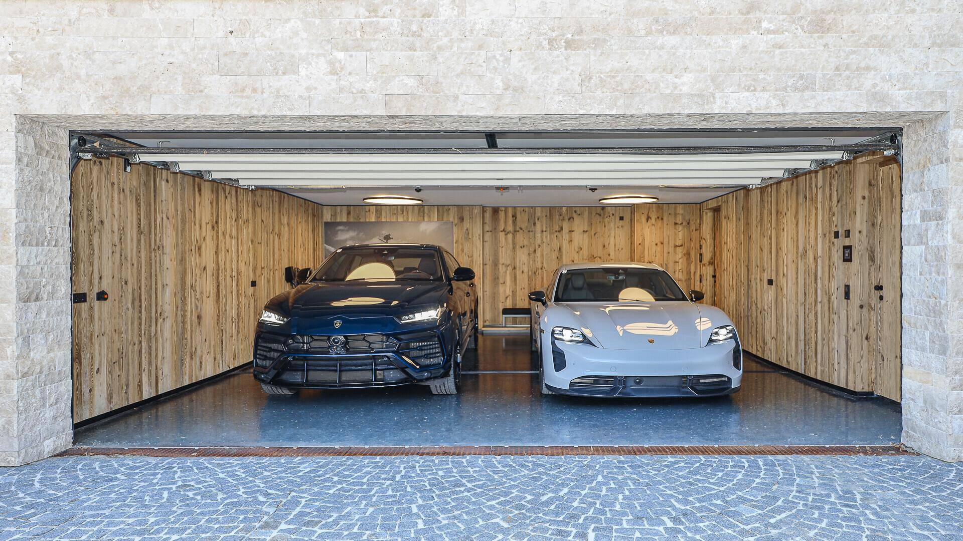 Geräumige Garage mit Holzverkleidung und Platz für zwei Luxusfahrzeuge.