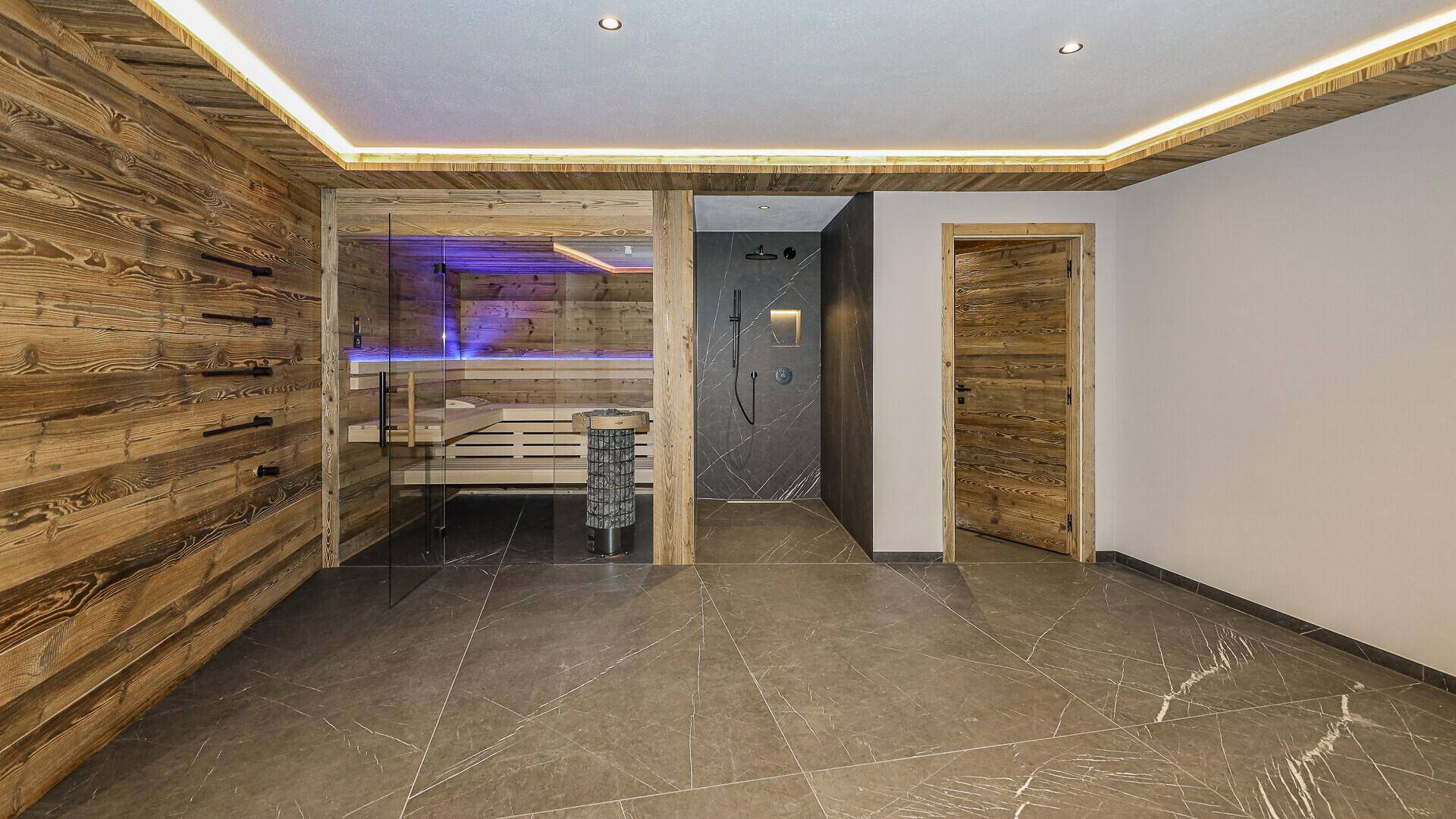 Geräumiges Badezimmer mit moderner Sauna, Regendusche und rustikalen Holzwänden.