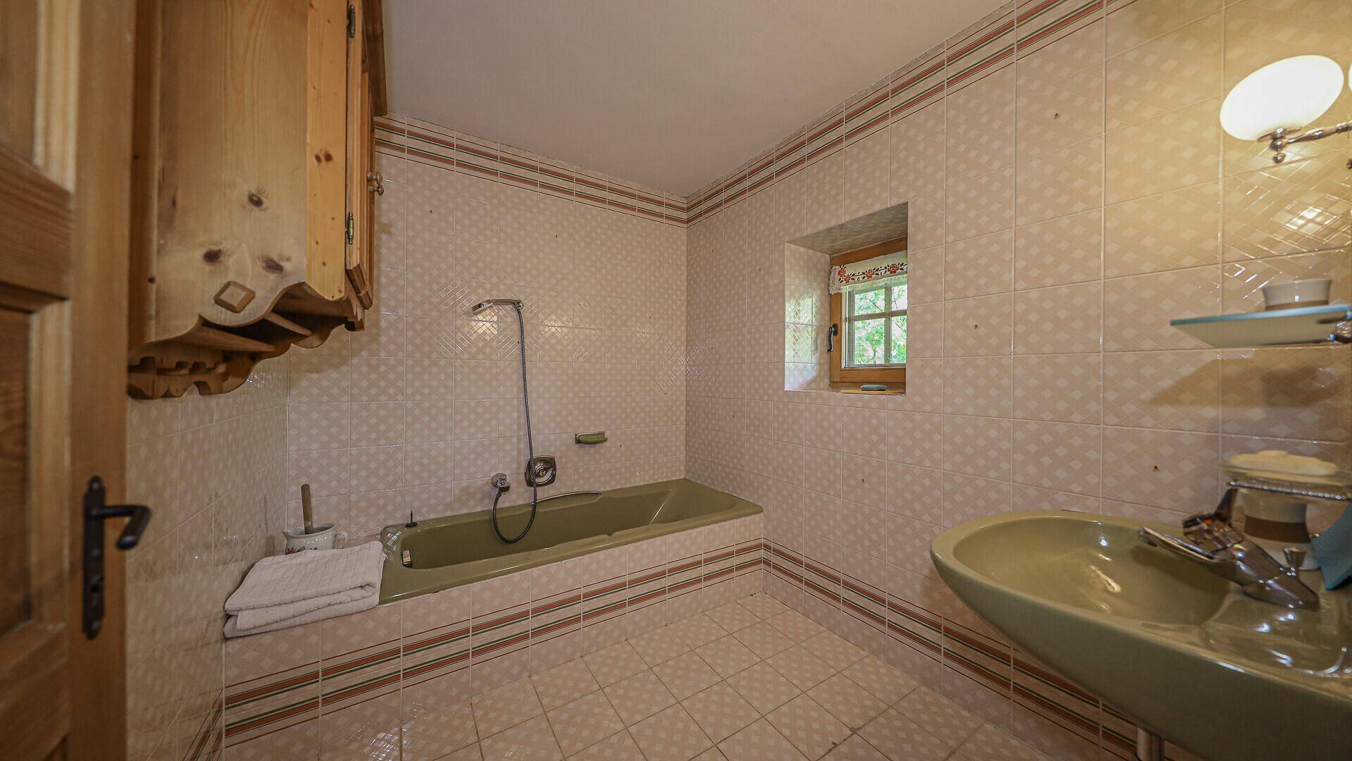 Badezimmer im Stil der 80er Jahre mit grünen Sanitärobjekten und rosa Fliesen.