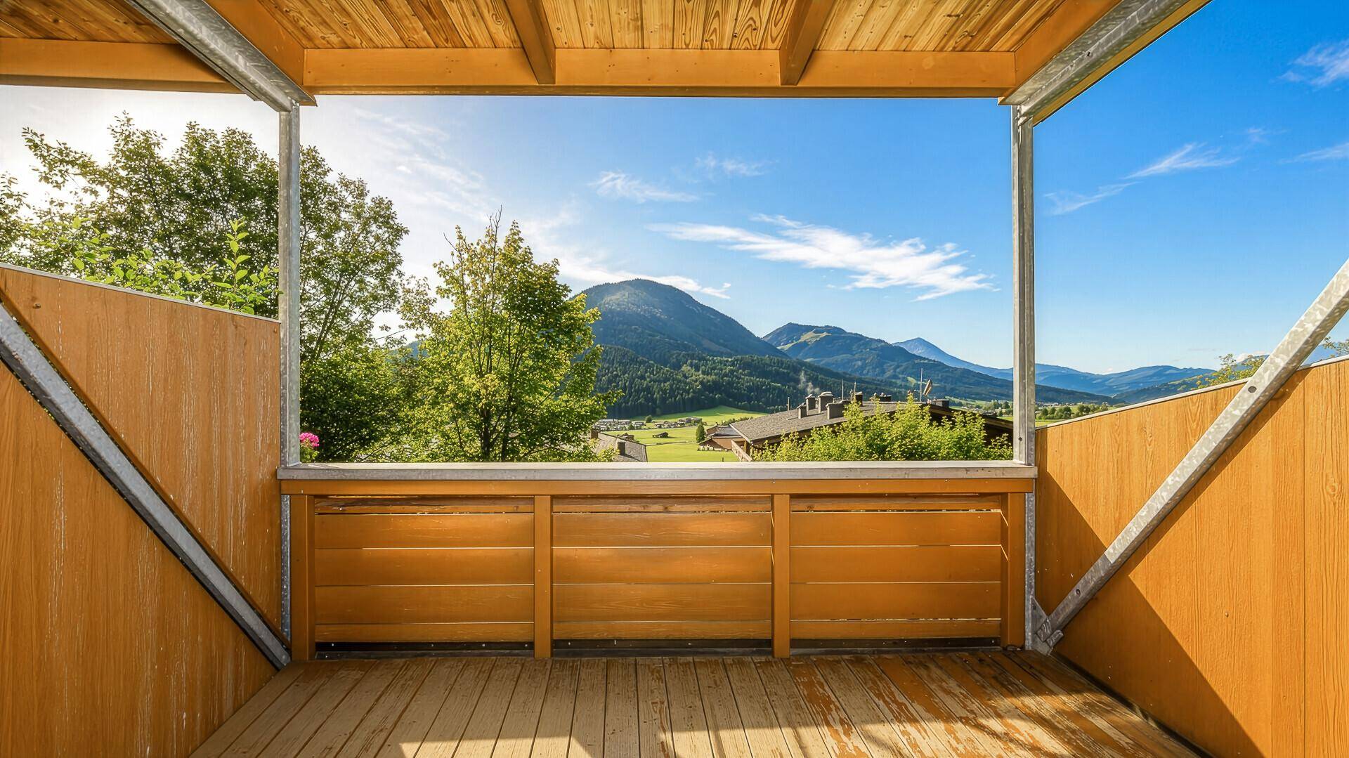Geräumiger Balkon mit Holzboden und weitem Blick auf die umliegende Berglandschaft.