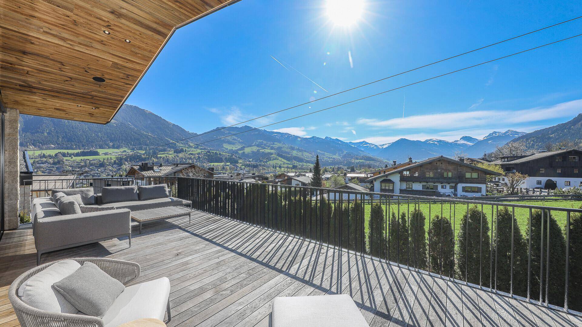 Geräumige Terrasse mit Lounge-Möbeln, Holzdeck und weitem Blick auf die alpine Umgebung.