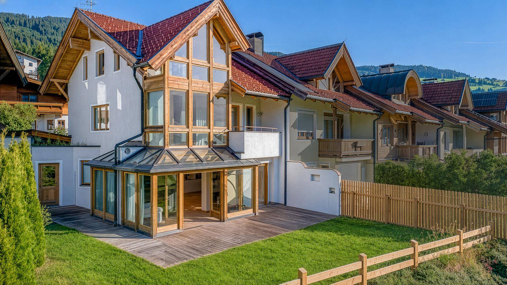 Attraktive Fassade des Hauses mit Holzelementen, großen Fenstern und traditionellem Ziegeldach.