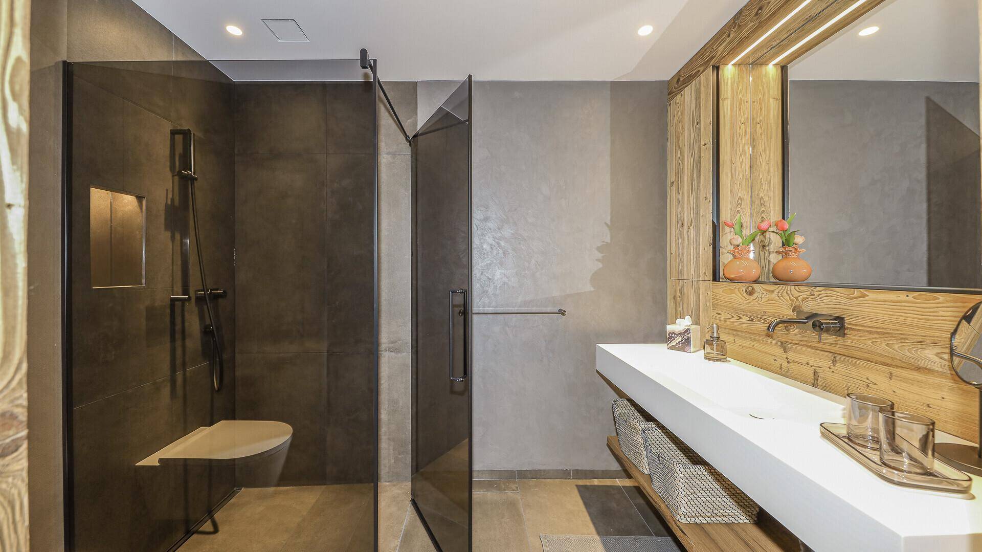 Elegantes Badezimmer mit begehbarer Dusche, modernem Waschtisch und Holzdetails.