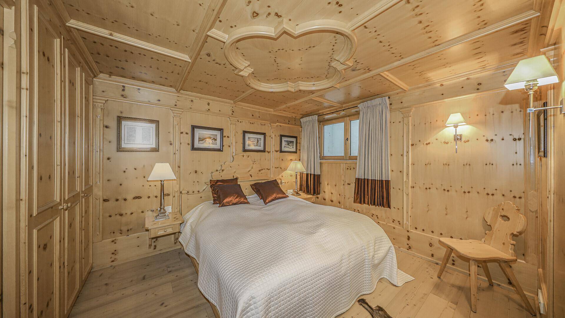 Schlafzimmer mit Holztäfelung, Einbauschränken und dekorativer Holzdecke.