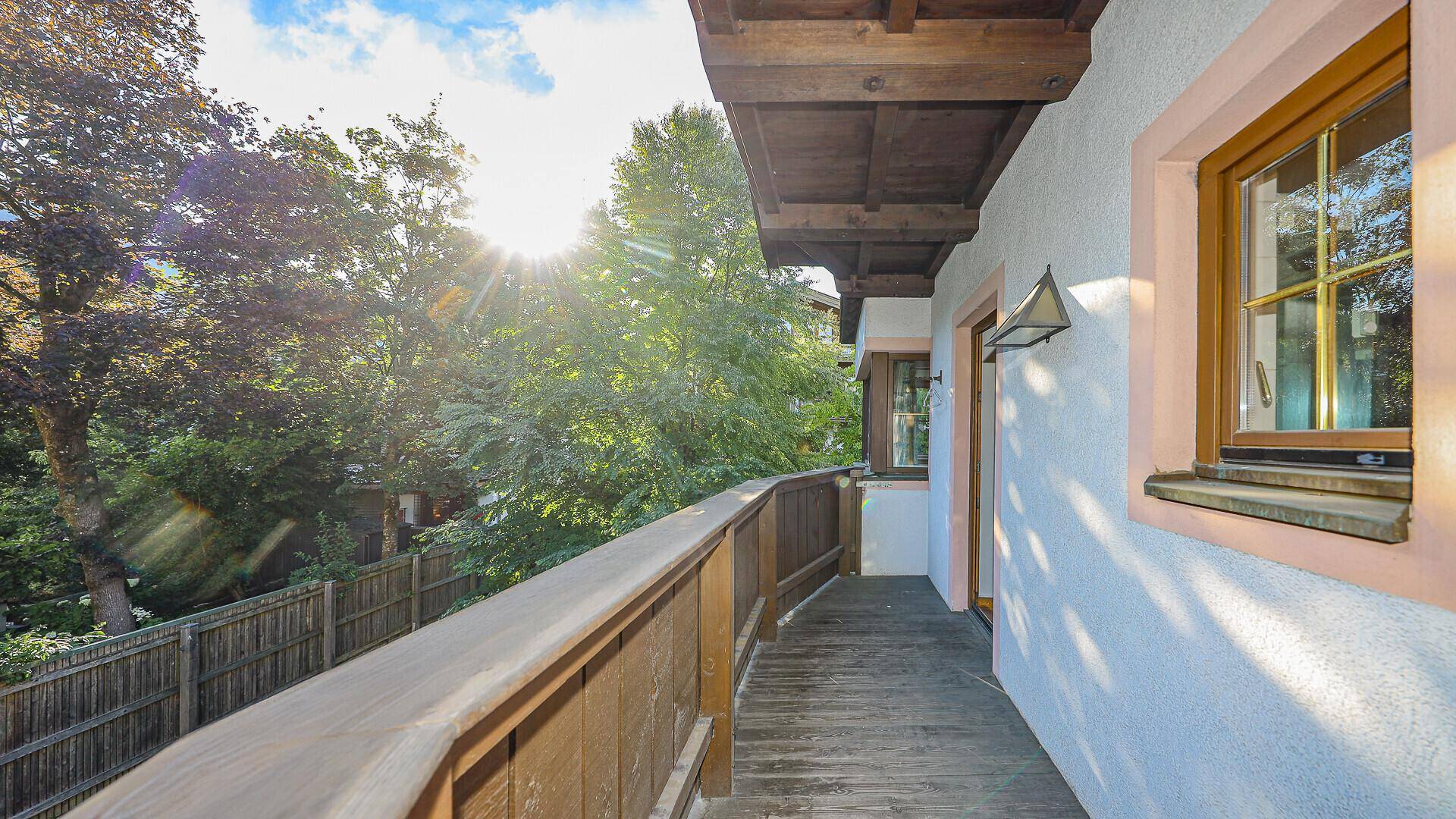 Sonniger Holzbalkon mit Blick auf die grüne Umgebung und viel Privatsphäre.