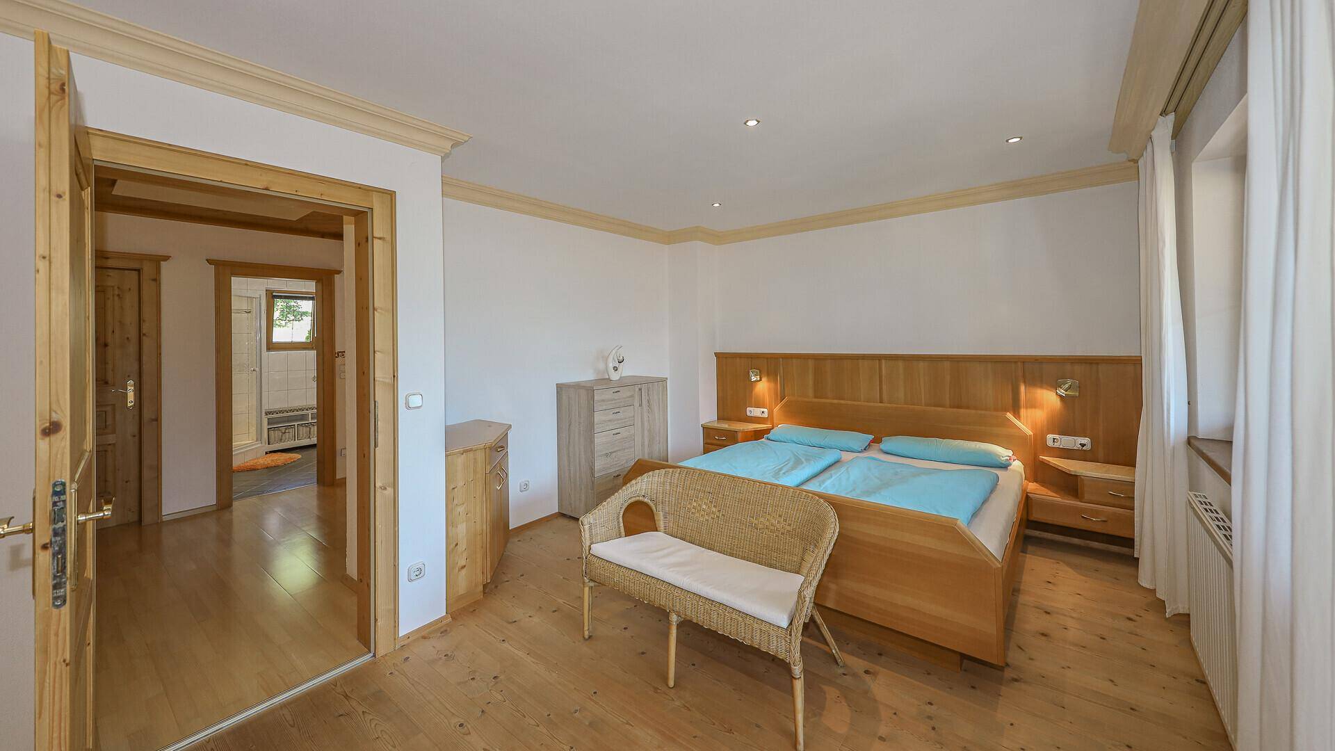 Geräumiges Schlafzimmer mit Doppelbett, Holzmöbeln und Zugang zu einem weiteren Raum.