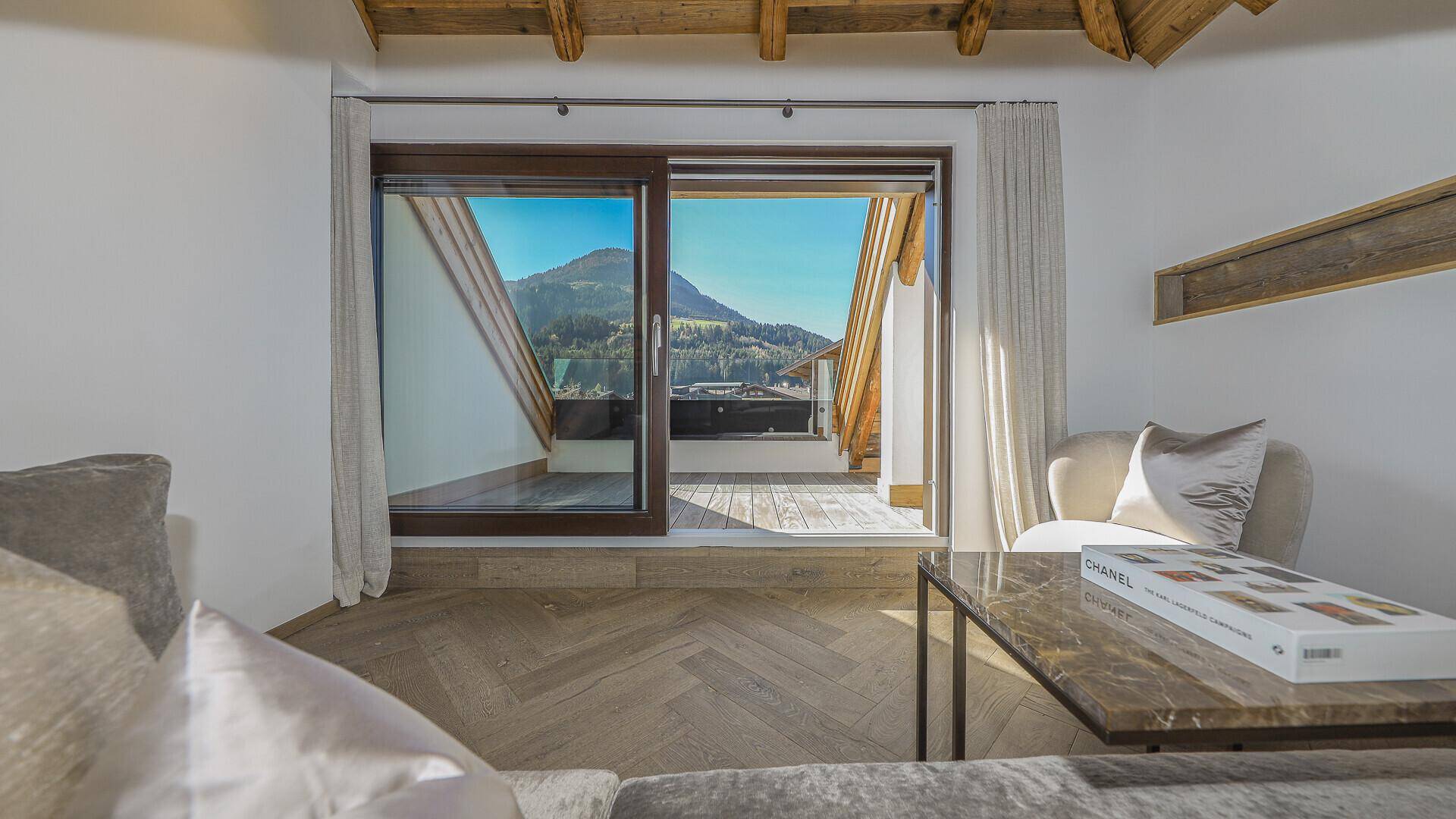 Heller Wohnbereich mit Schiebetür zur Terrasse und Panoramablick auf die Berge.