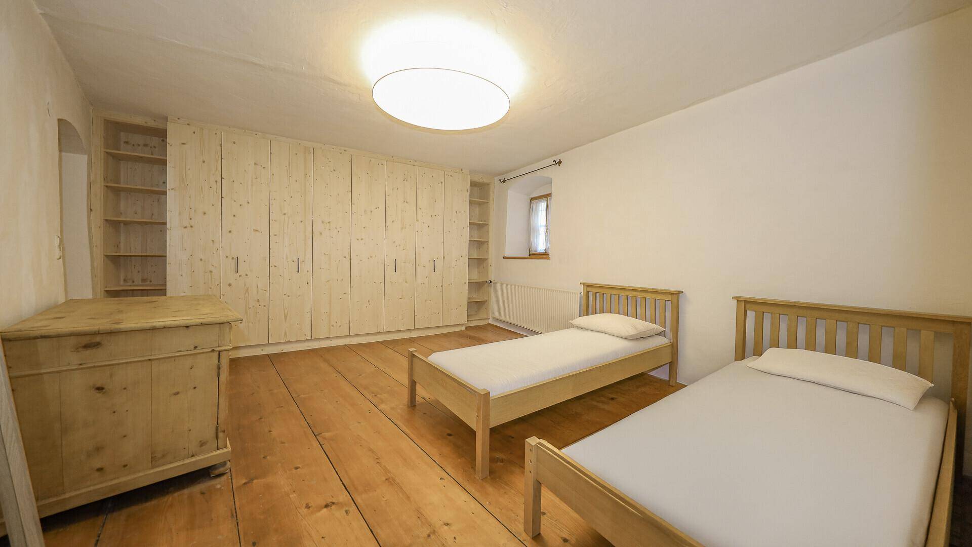 Gemütliches Schlafzimmer mit zwei Einzelbetten, großen Einbauschränken aus Holz und Dielenboden.