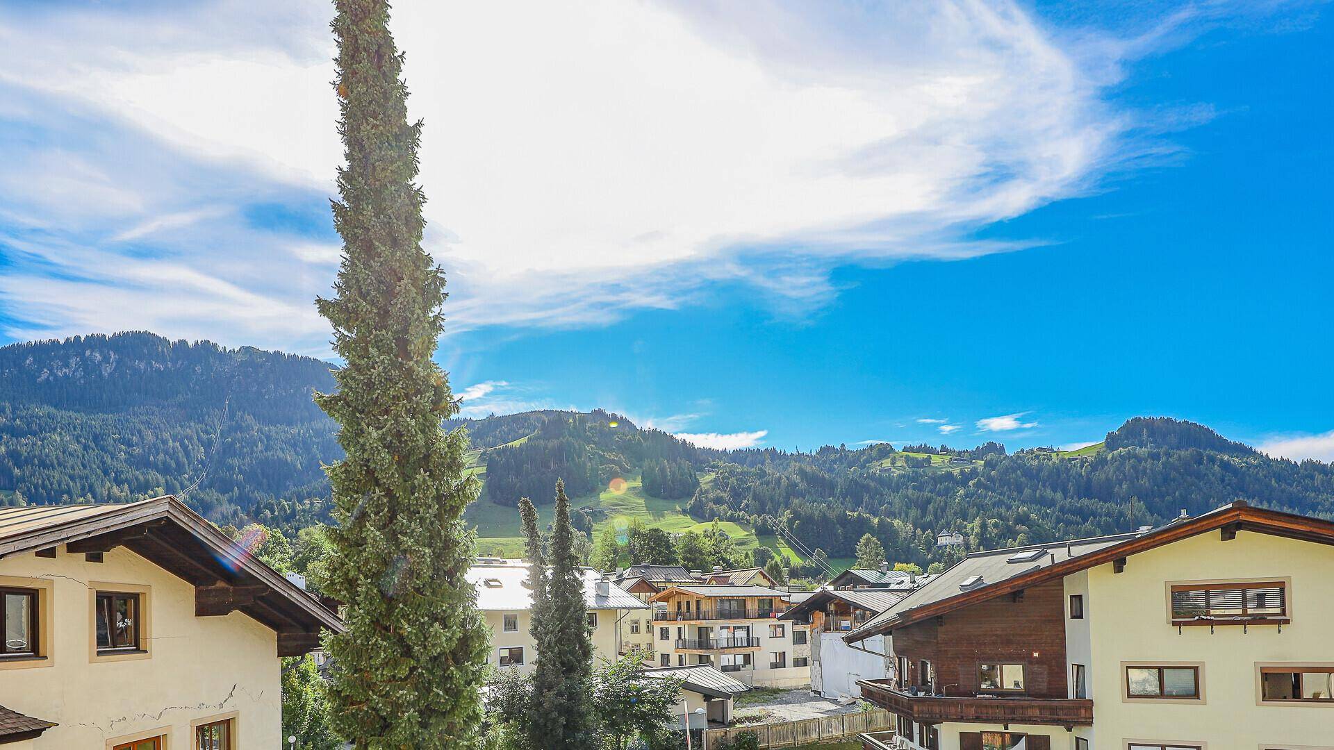 Malerische Berglandschaft mit traditionellen Häusern und einem weiten Blick auf die grüne Umgebung.