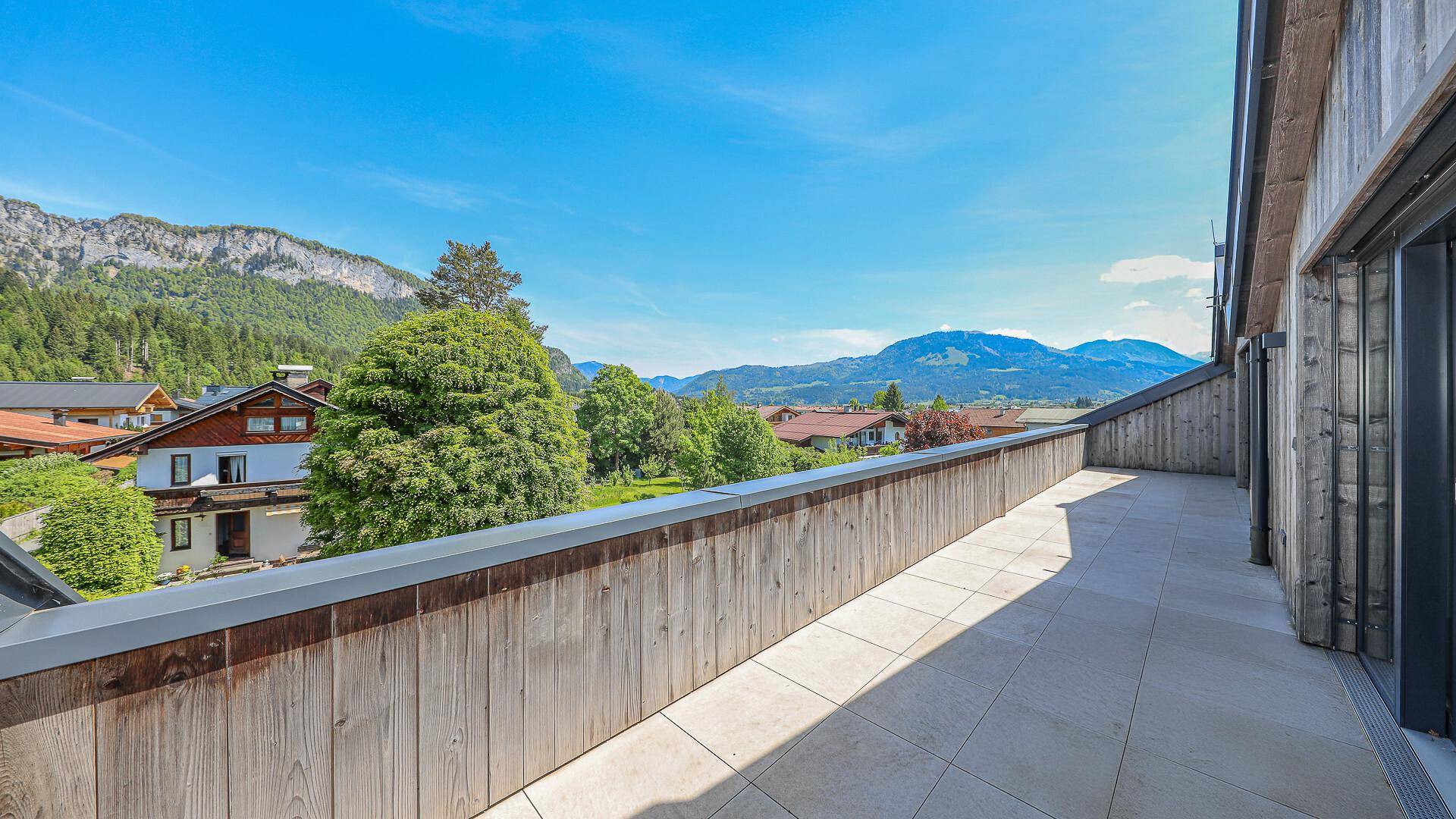 Lange Terrasse mit Holzwänden und Panoramablick auf die umliegende Landschaft.