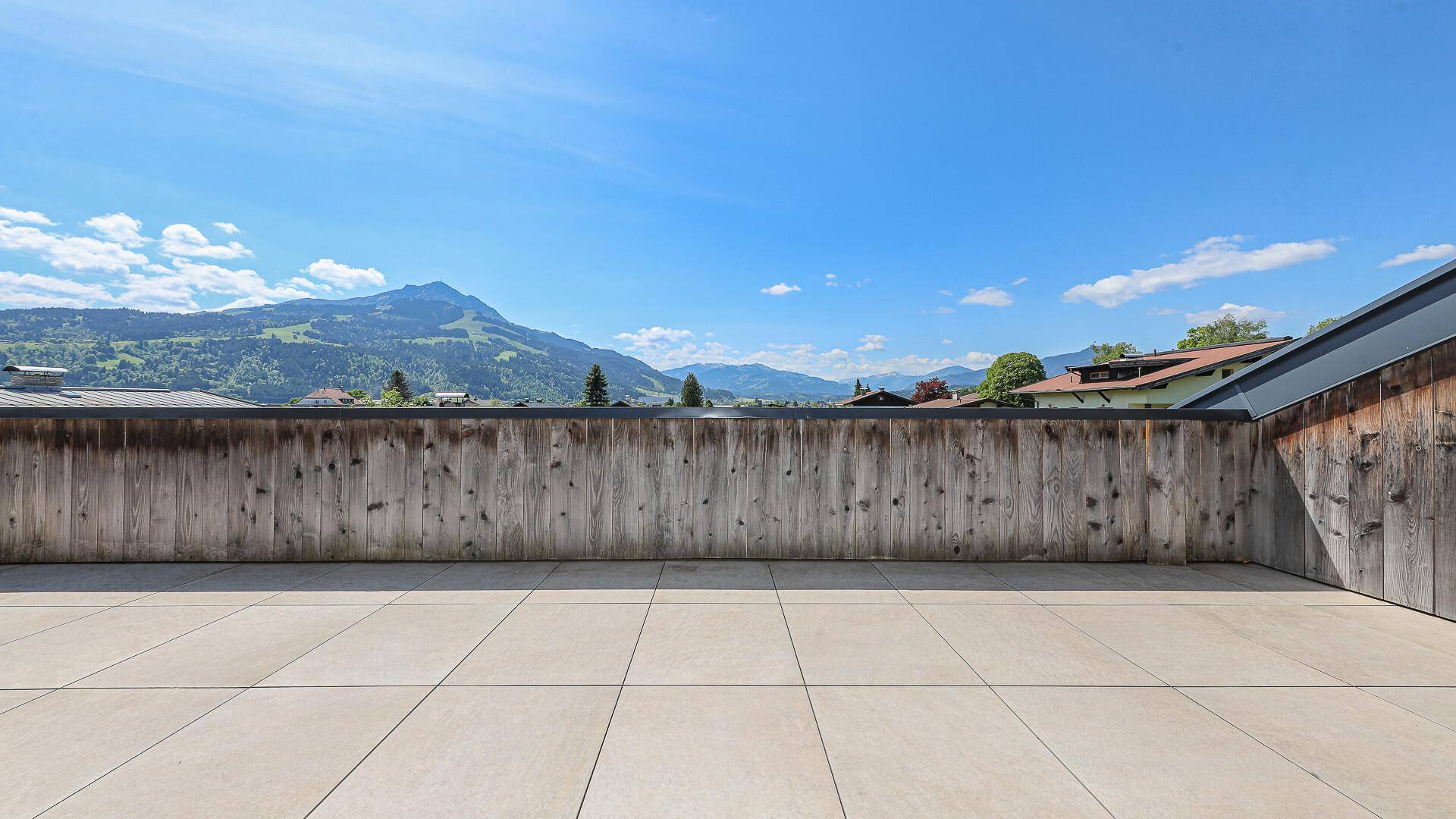 Geräumige Dachterrasse mit weitem Bergblick unter blauem Himmel.
