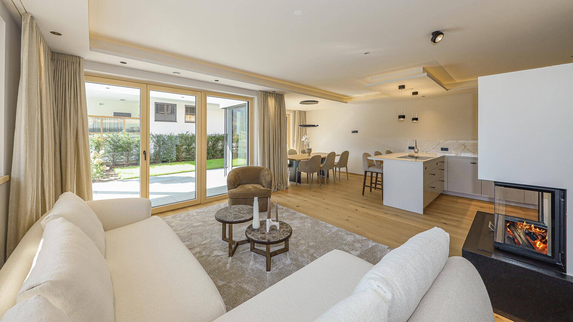 Geräumiger Wohn-Essbereich mit Kamin, Zugang zum Garten und offener Küche, perfekt für Familien.
