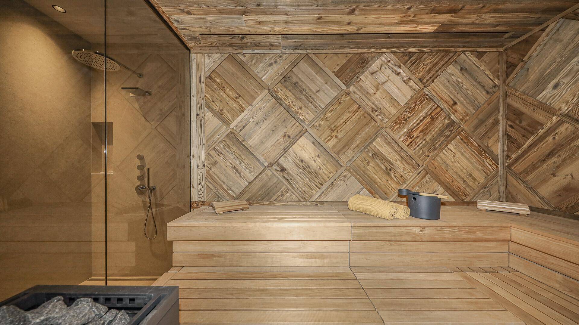 Geräumige Holzsauna mit bequemen Bänken und integrierter Dusche für ein entspannendes Erlebnis.