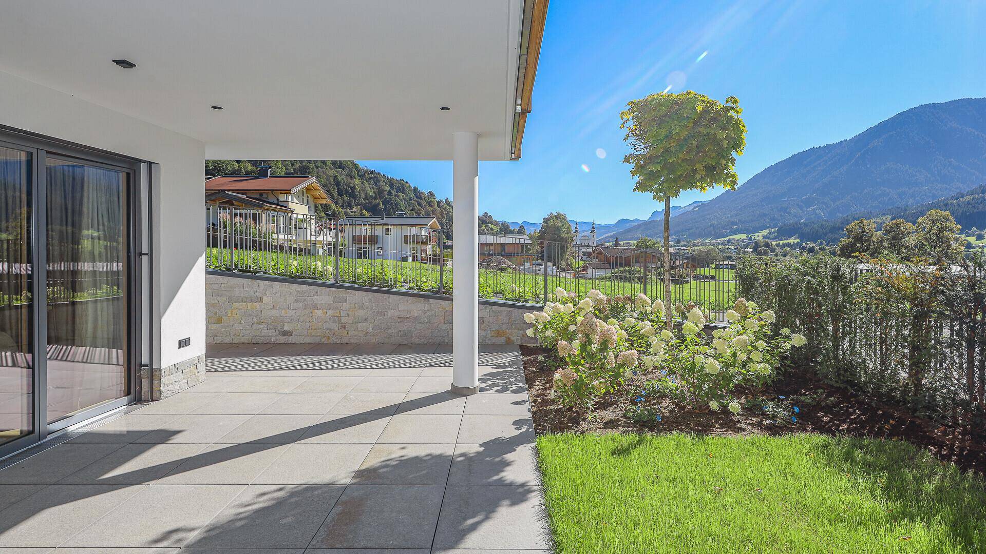 Geräumige Terrasse mit Blick auf die Berge und den Garten, ideal für Entspannung im Freien.