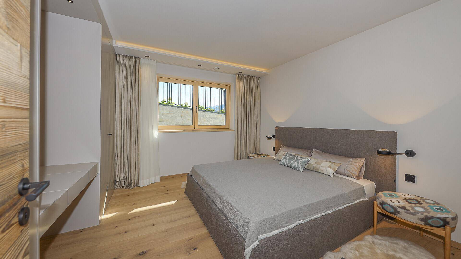 Gemütliches Schlafzimmer mit Doppelbett, Holzboden und Fenster mit Bergblick.