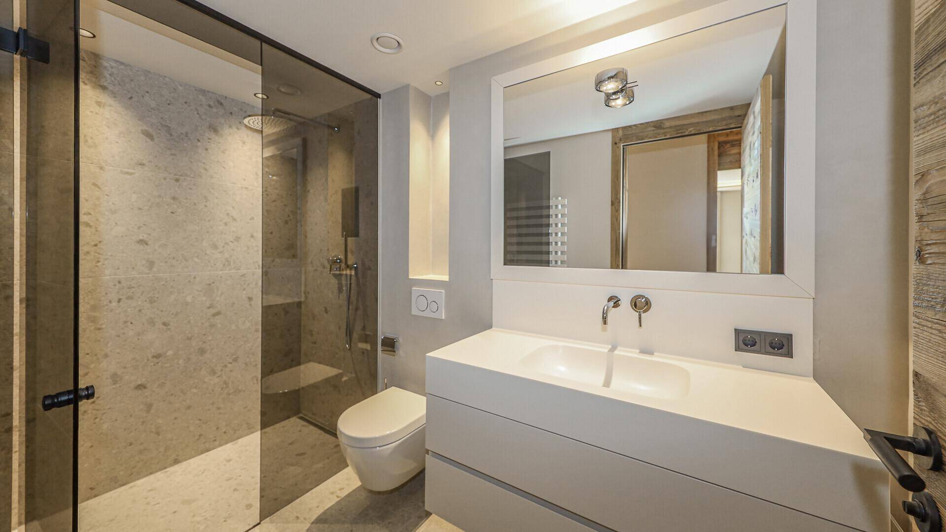 Modernes Badezimmer mit begehbarer Dusche, wandhängendem WC und Doppelwaschbecken.
