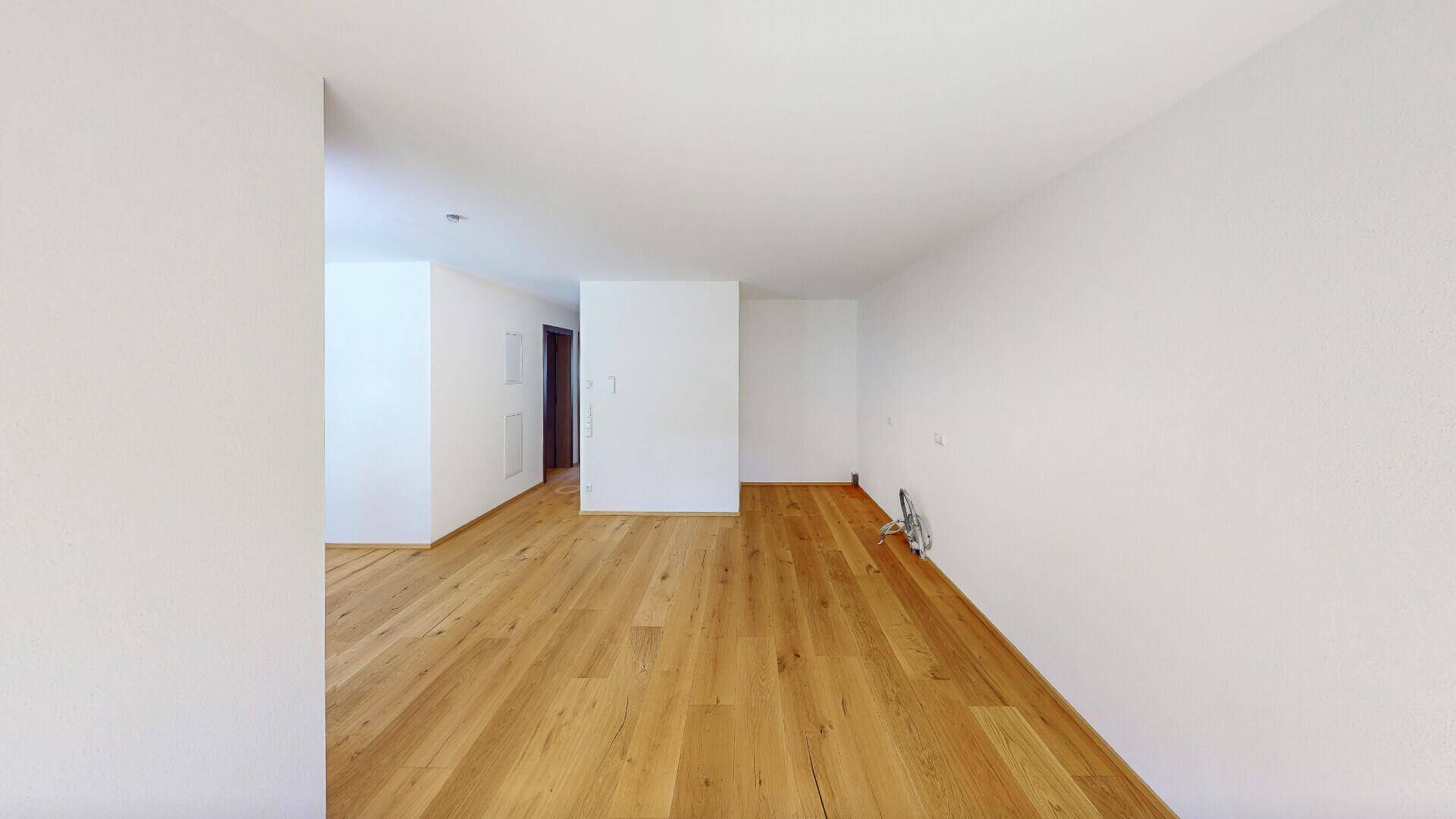 Heller, leerer Raum mit neuem Holzboden und weißen Wänden, bereit zur individuellen Gestaltung.