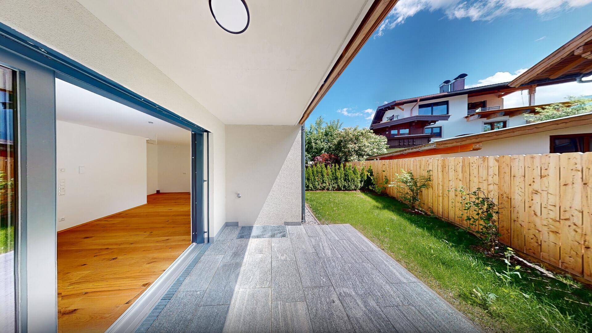 Geräumige Terrasse mit Fliesenboden und direktem Zugang zum Garten, ideal für entspannte Stunden im Freien.
