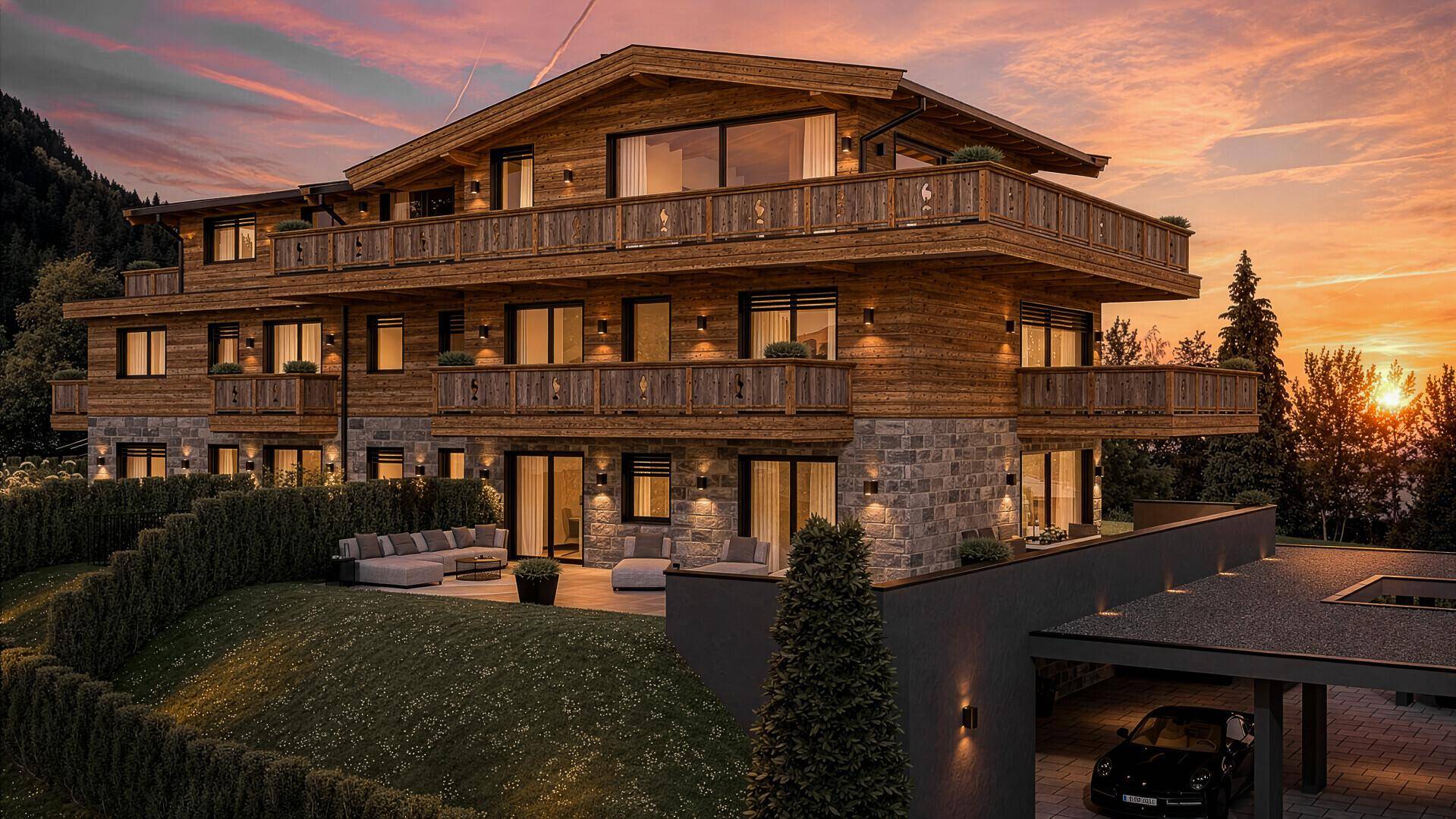 Alpenresidenz bei Sonnenuntergang mit beleuchteten Balkonen und einer gemütlichen Terrasse.