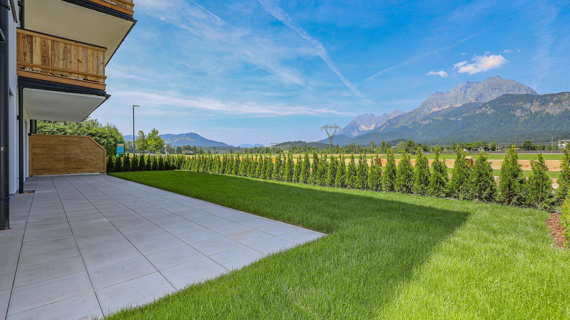 Große, unmöblierte Terrasse mit Rasenfläche und beeindruckendem Bergblick.