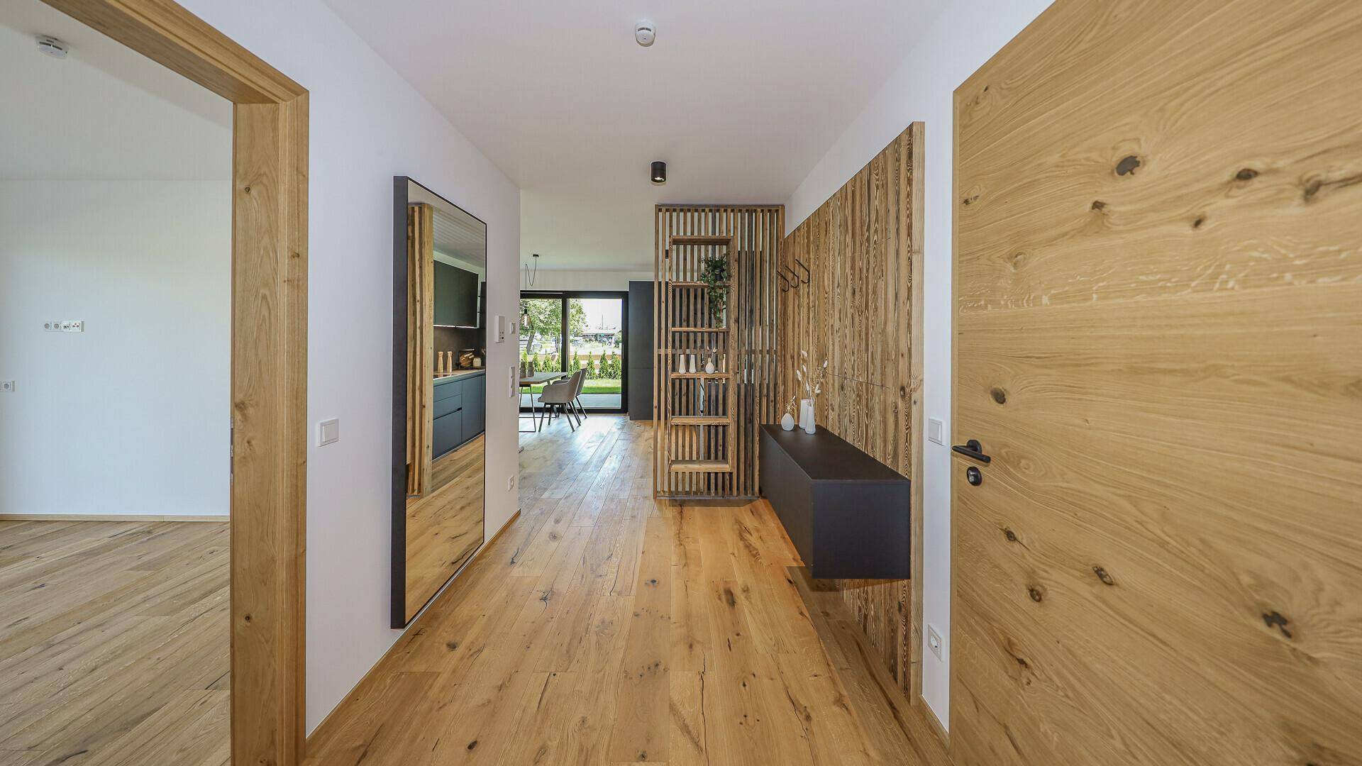 Heller Flur mit Holzboden, Garderobe und Blick in den offenen Wohnbereich.