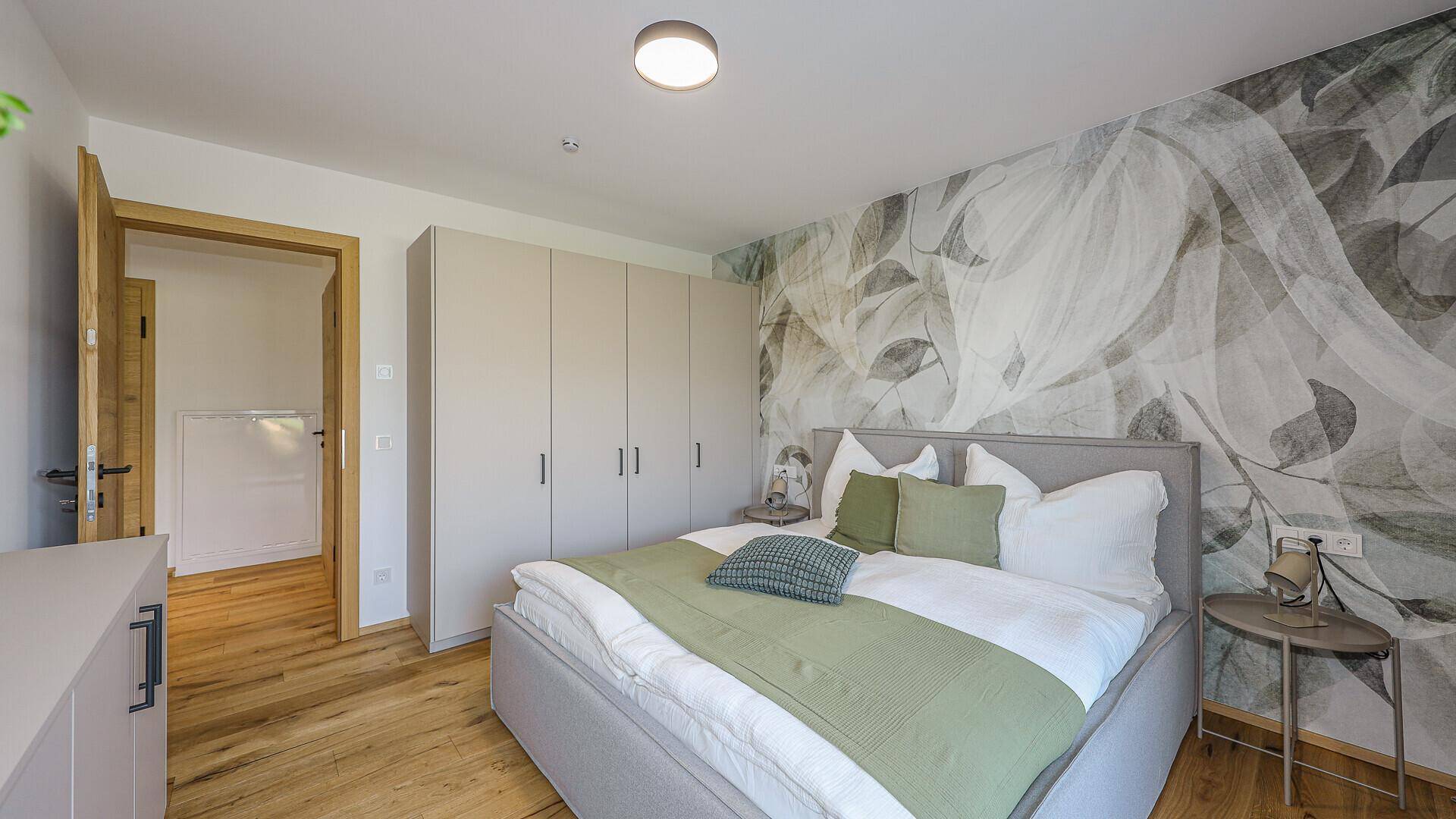Modernes Schlafzimmer mit floraler Tapete, Einbauschränken und Holzboden.