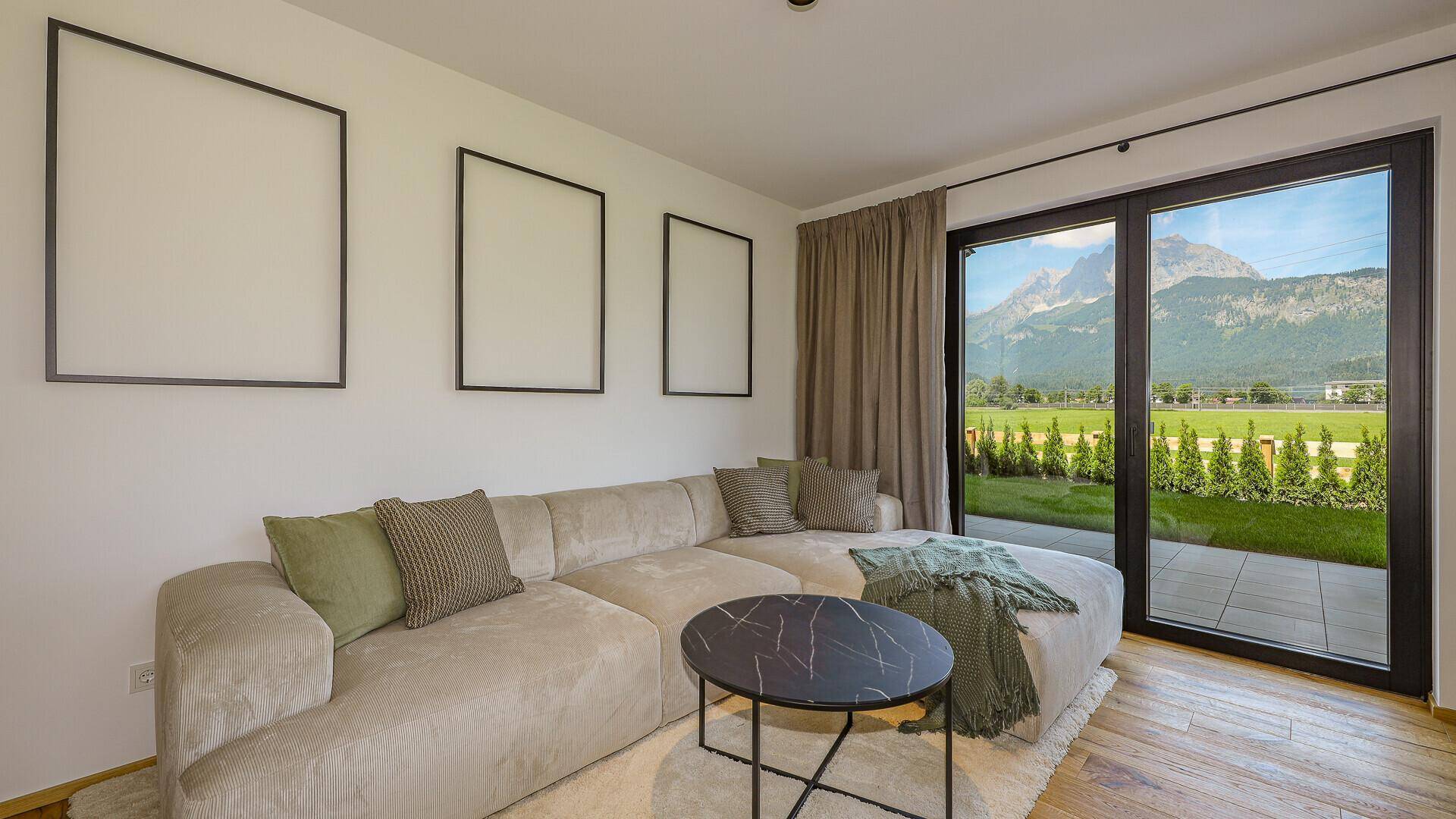 Gemütliches Wohnzimmer mit großem Sofa, Holzboden und direktem Zugang zur Terrasse mit Bergblick.