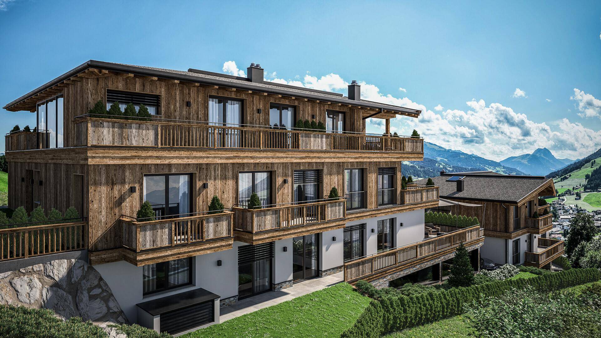 Seitliche Ansicht des modernen Chalets mit Holzverkleidung und zahlreichen Balkonen, die einen weiten Bergblick bieten.