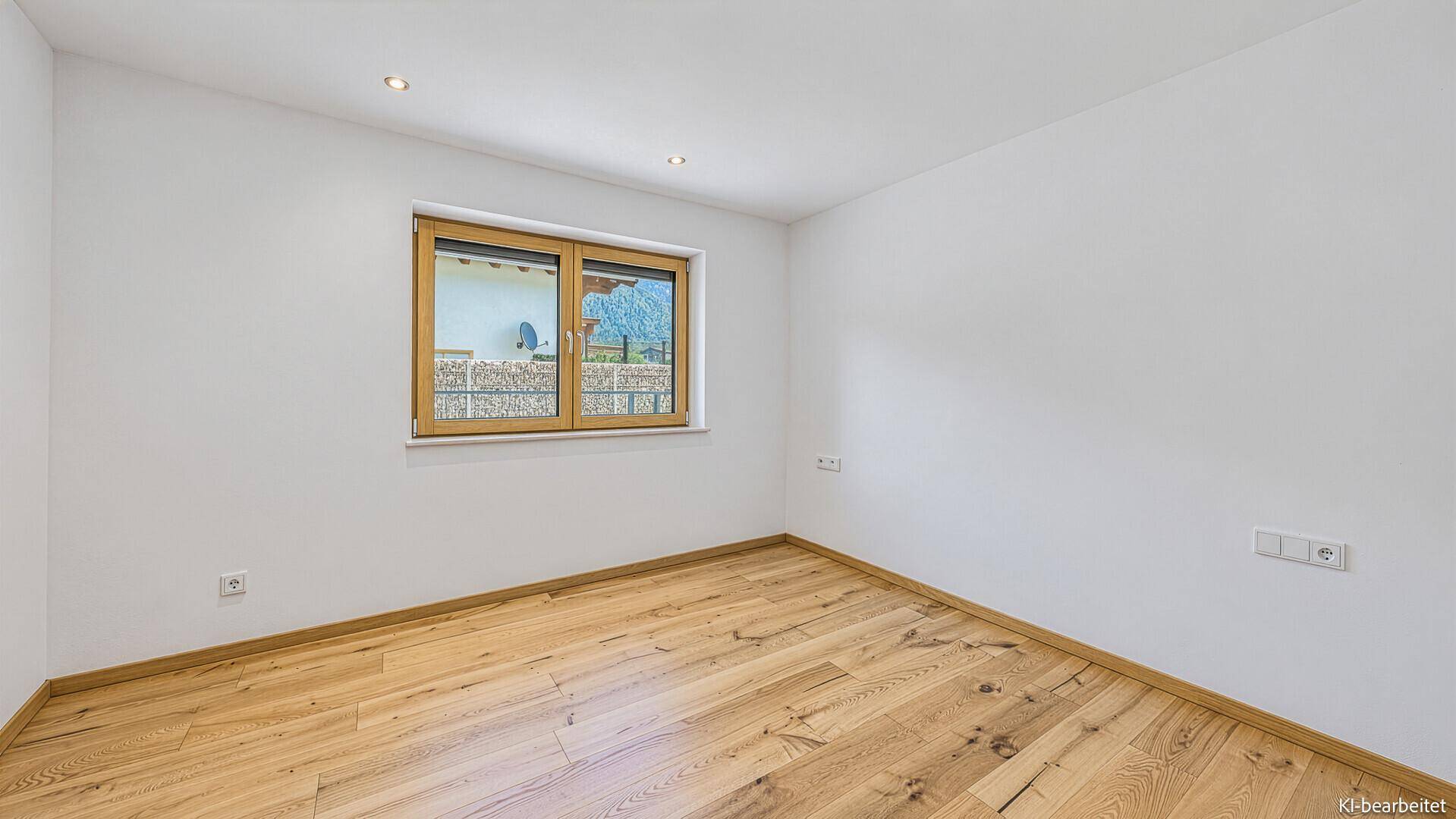 Helles Schlafzimmer mit Holzboden und Fenster mit Ausblick.