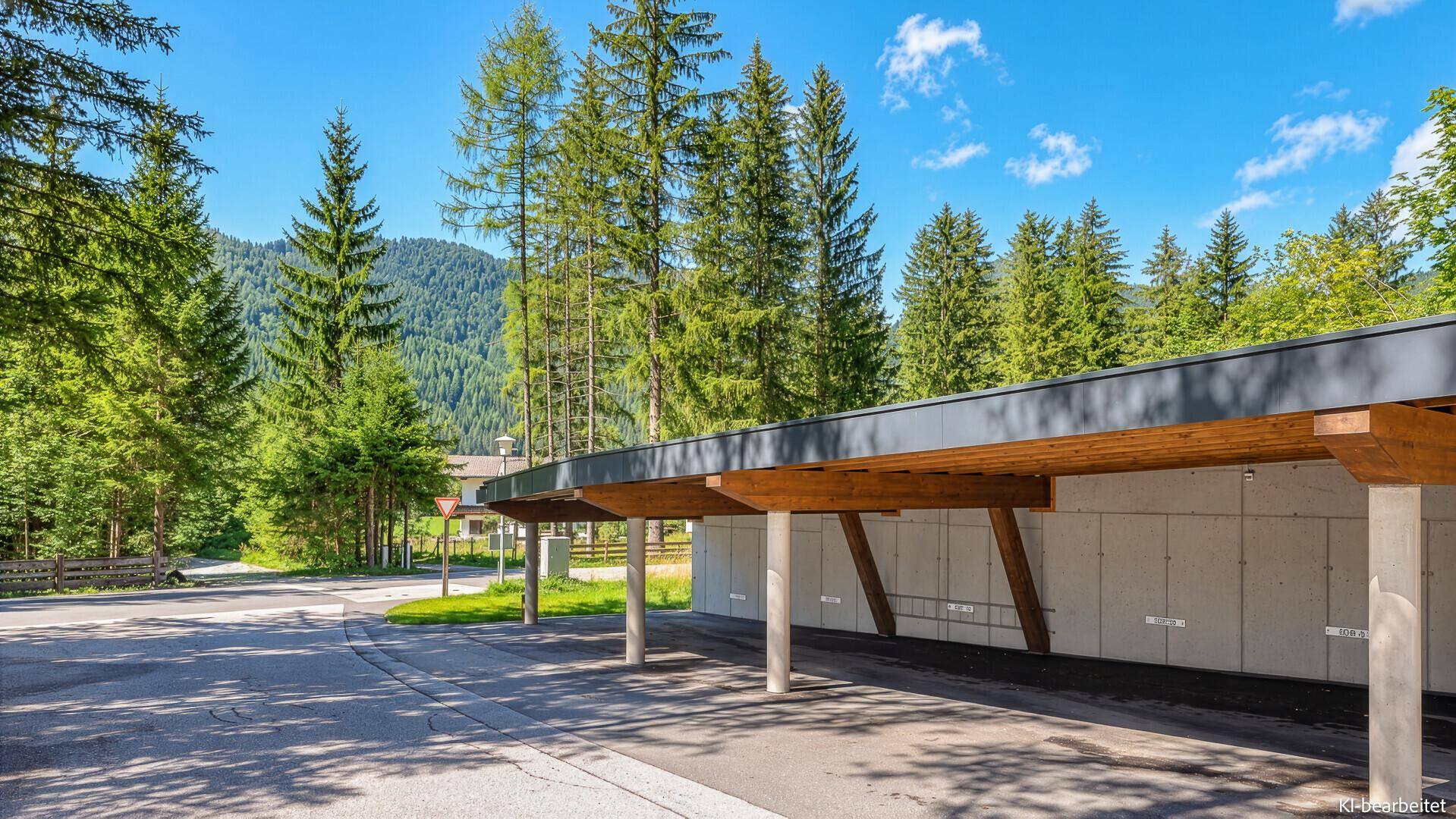 Überdachter Parkplatz mit Holzkonstruktion und umgeben von hohen Bäumen.
