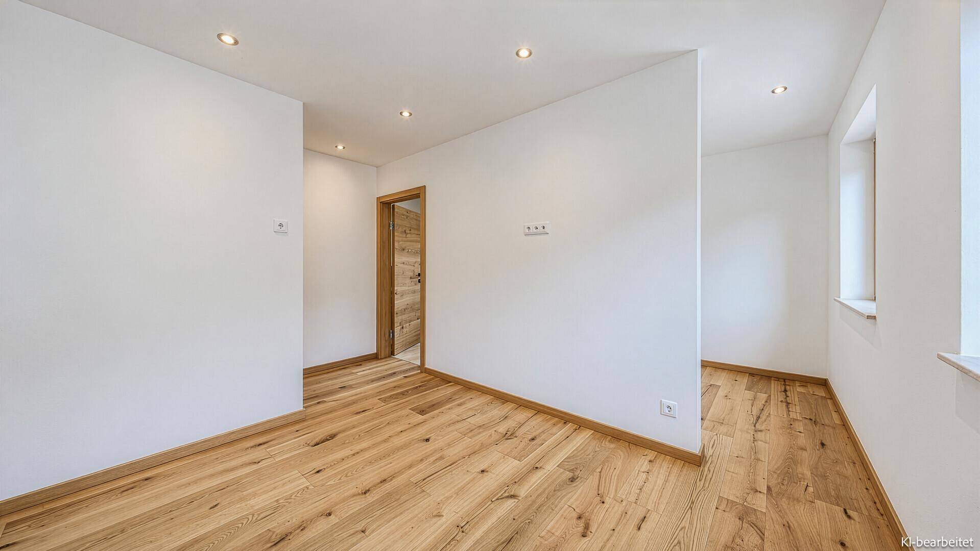 Leerer Raum mit Holzboden und weiß gestrichenen Wänden.