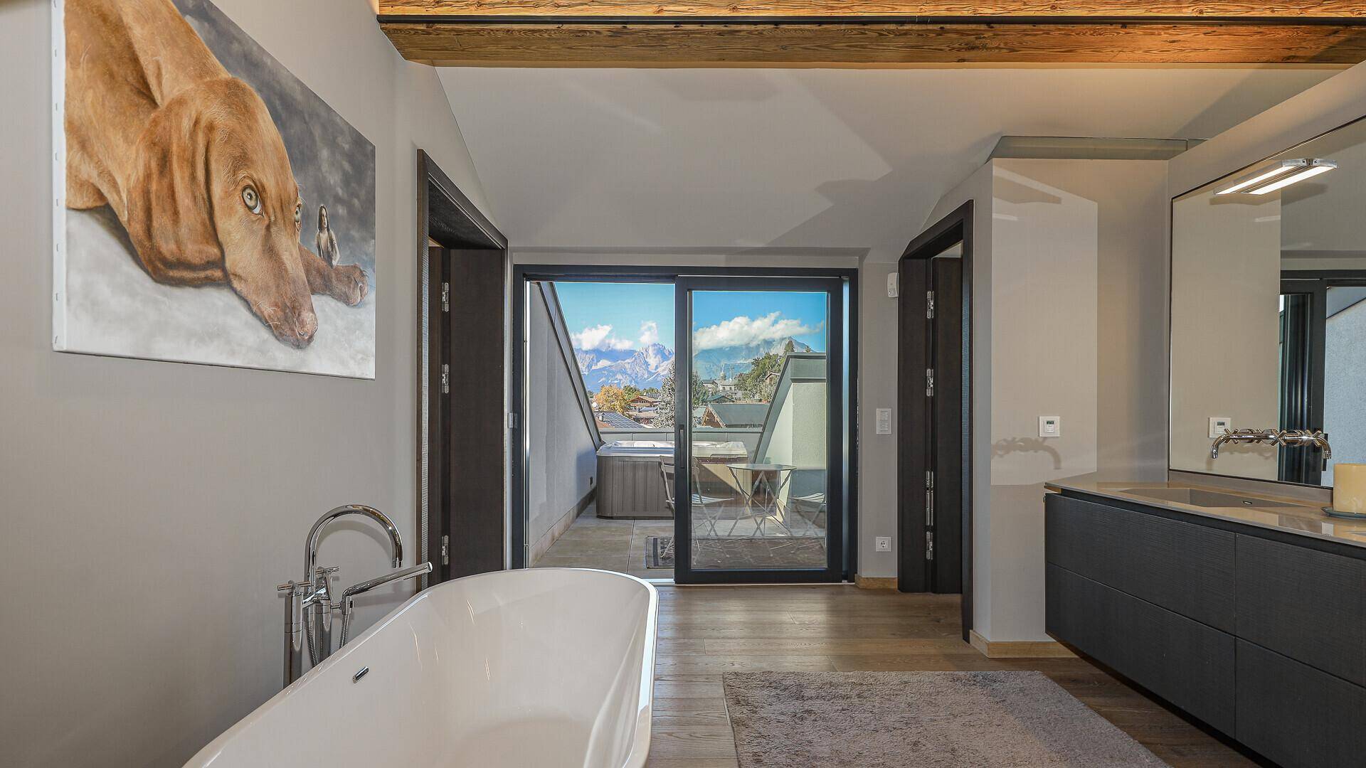 Modernes Badezimmer mit freistehender Badewanne, Doppelwaschbecken und Bergblick vom Balkon.