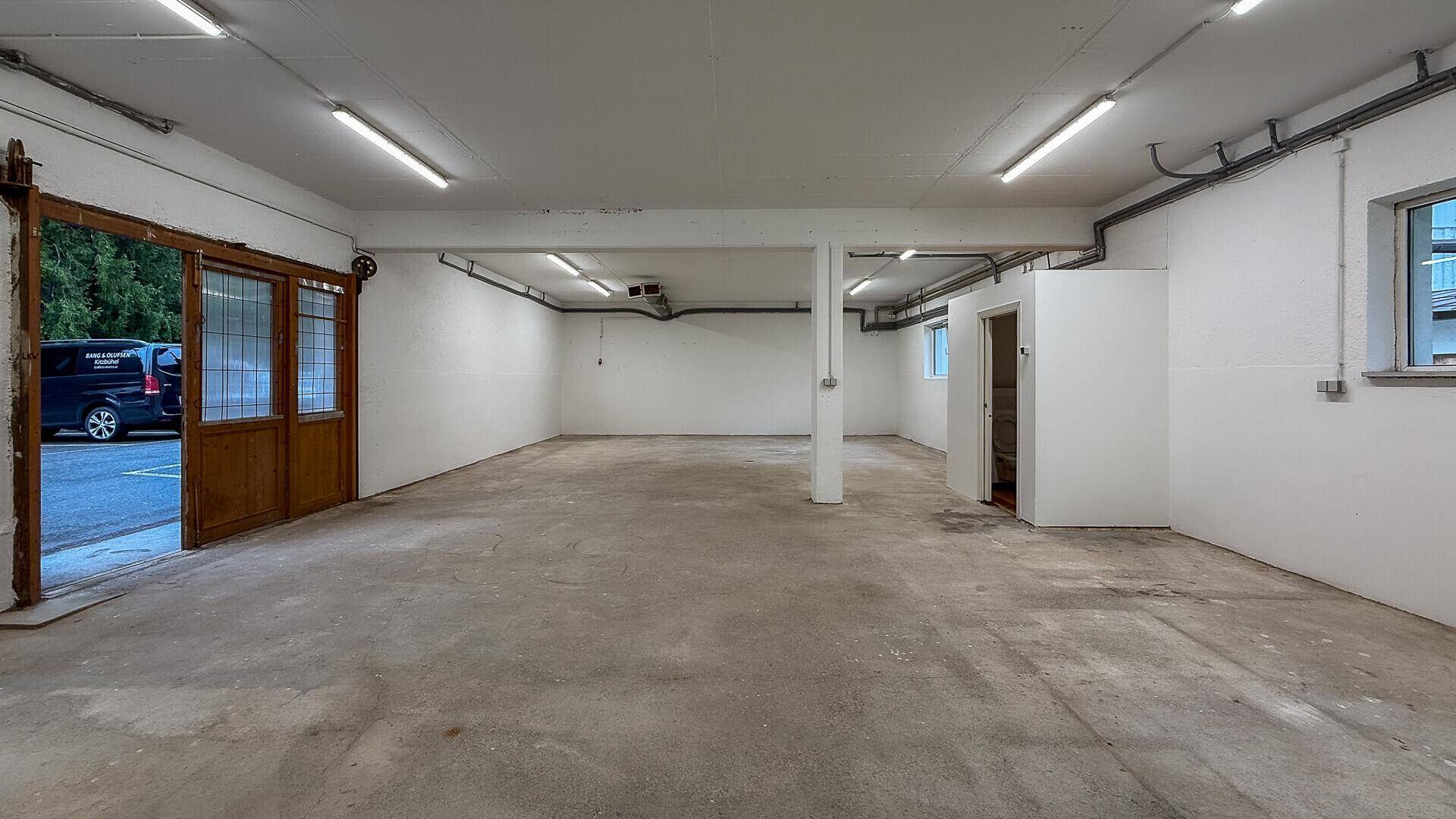 Heller Lagerraum mit Betonboden und großer Schiebetür, die den Zugang zum Außenbereich ermöglicht.