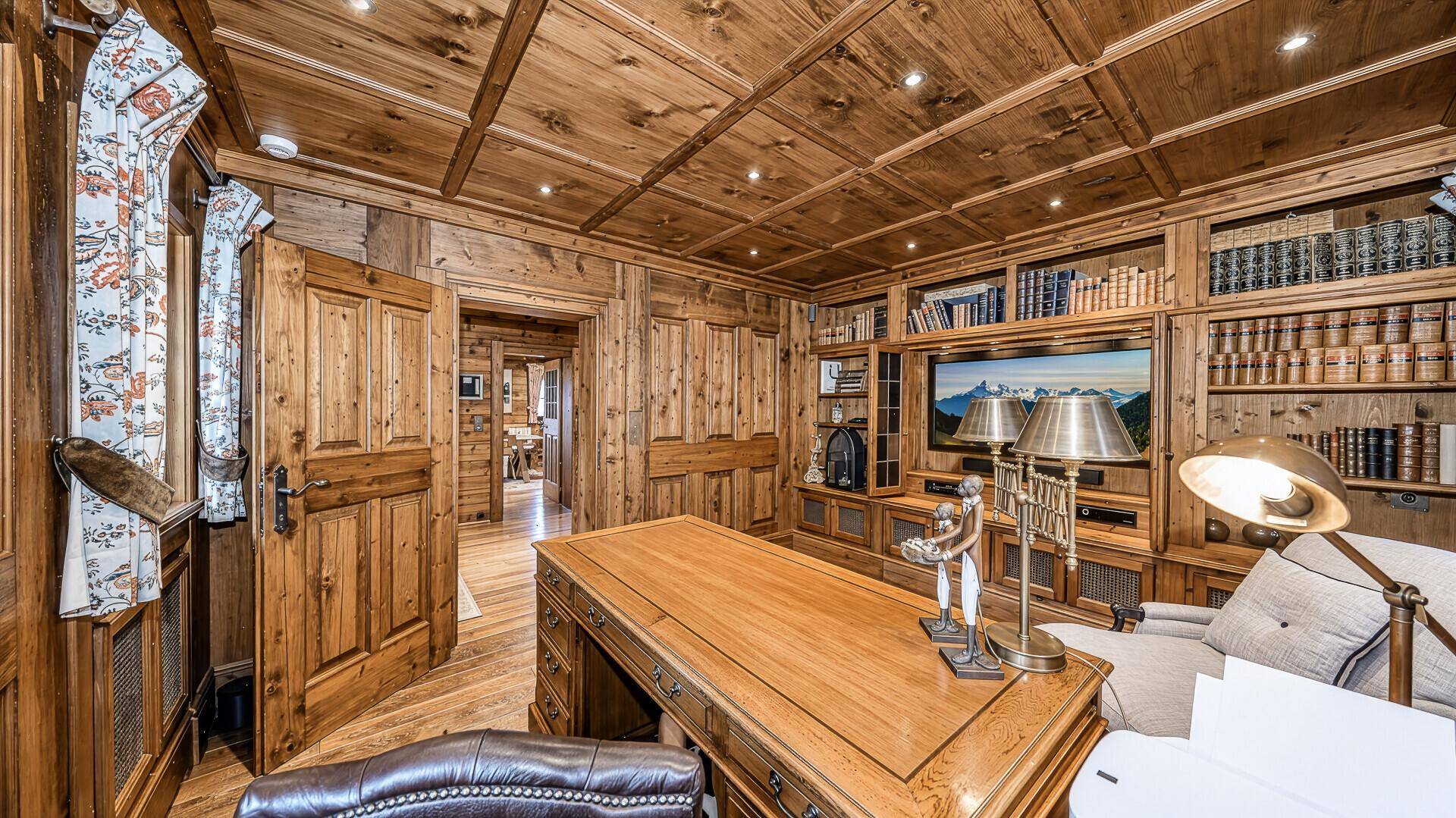 Traditionelles Arbeitszimmer mit Holzvertäfelung, Einbauregalen und großem Schreibtisch im alpinen Stil.