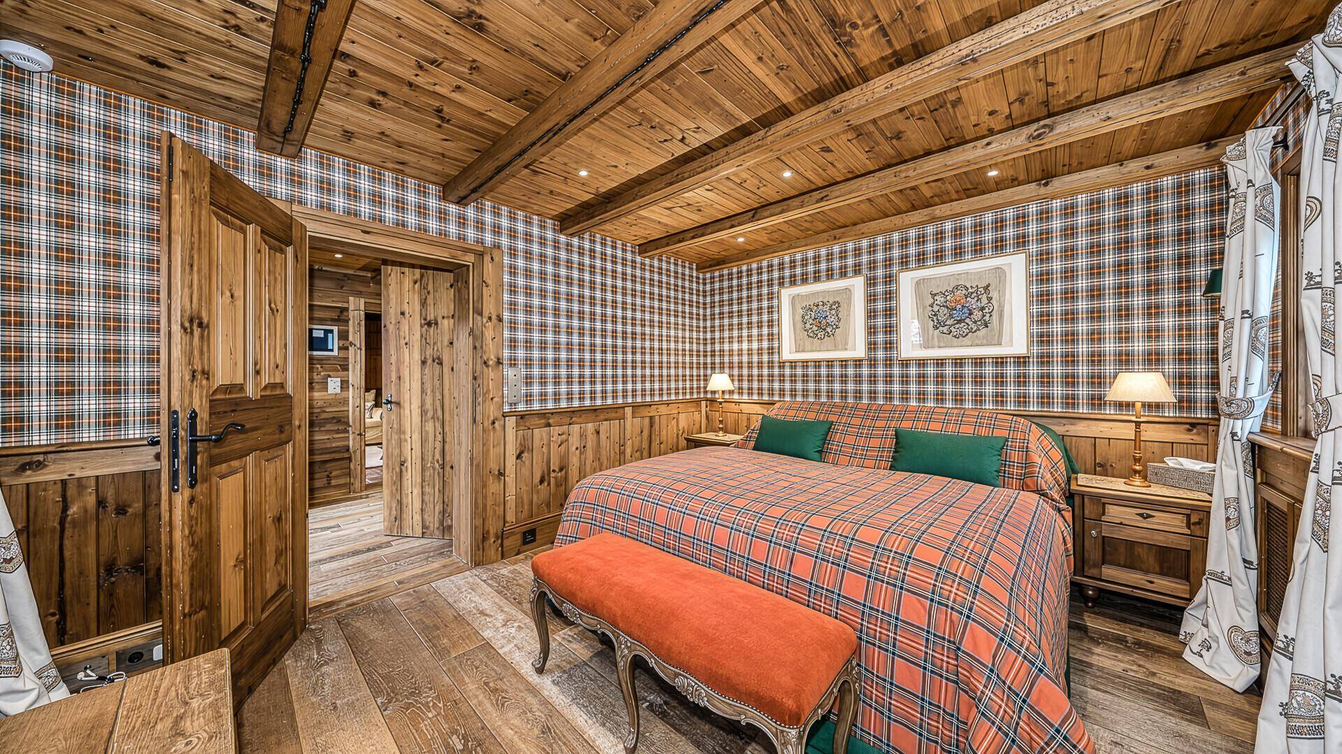 Rustikales Schlafzimmer mit Holzbalkendecke, karierter Tapete und traditionellen Holzmöbeln.