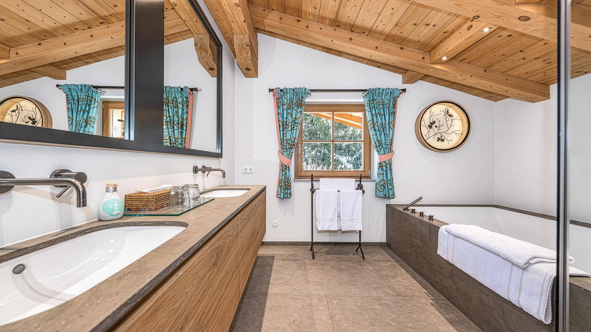 Modernes Badezimmer mit Badewanne, Doppelwaschbecken und Fenster mit Bergblick.